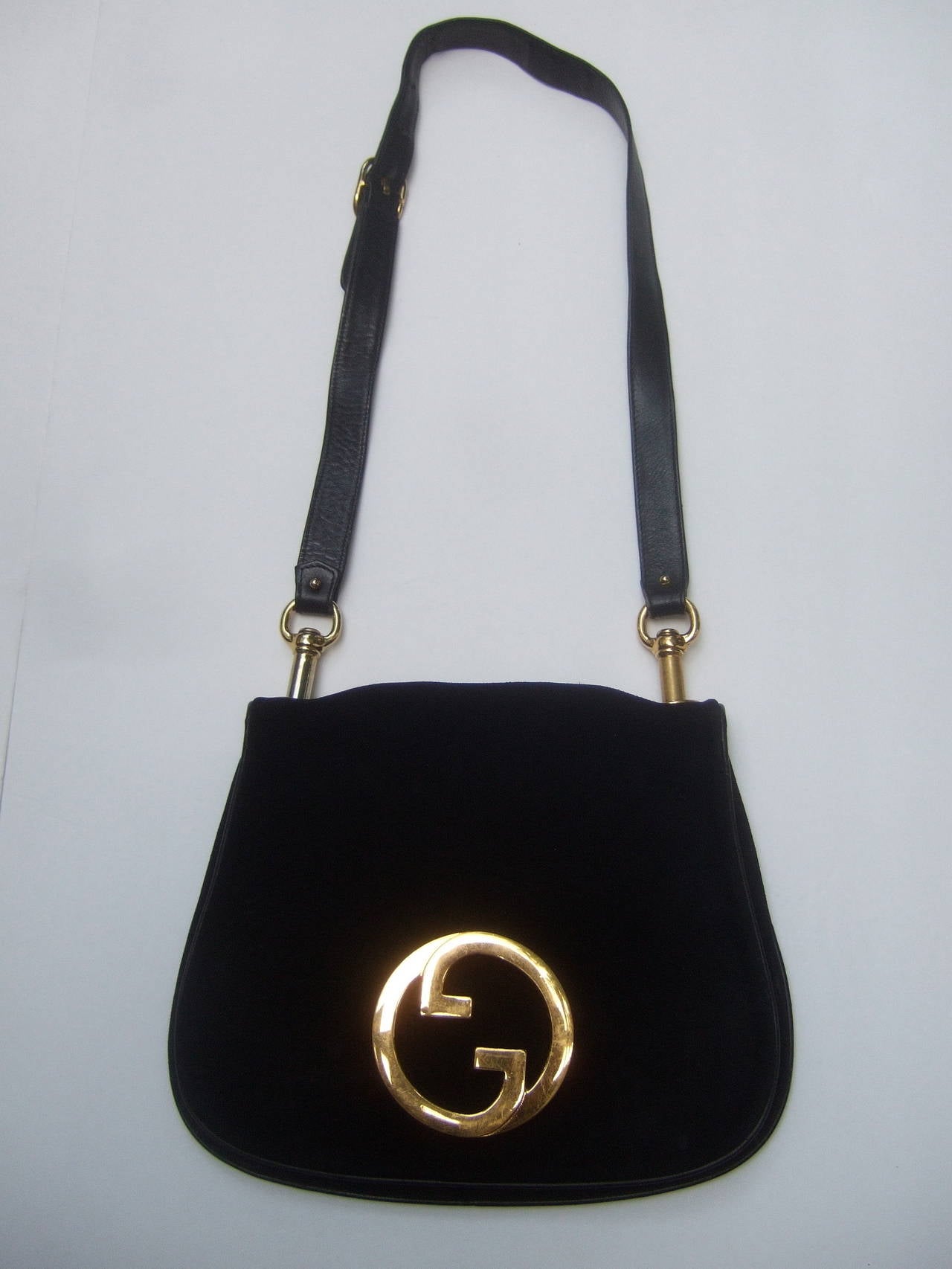 Gucci Italy Sleek black suede doeskin suede shoulder bag x 1970
The chic Italian handbag is covered with plush black suede
The front cover is adorned with Gucci's massive gilt metal
interlocked G.G. initials 

The iconic Gucci blondie shoulder