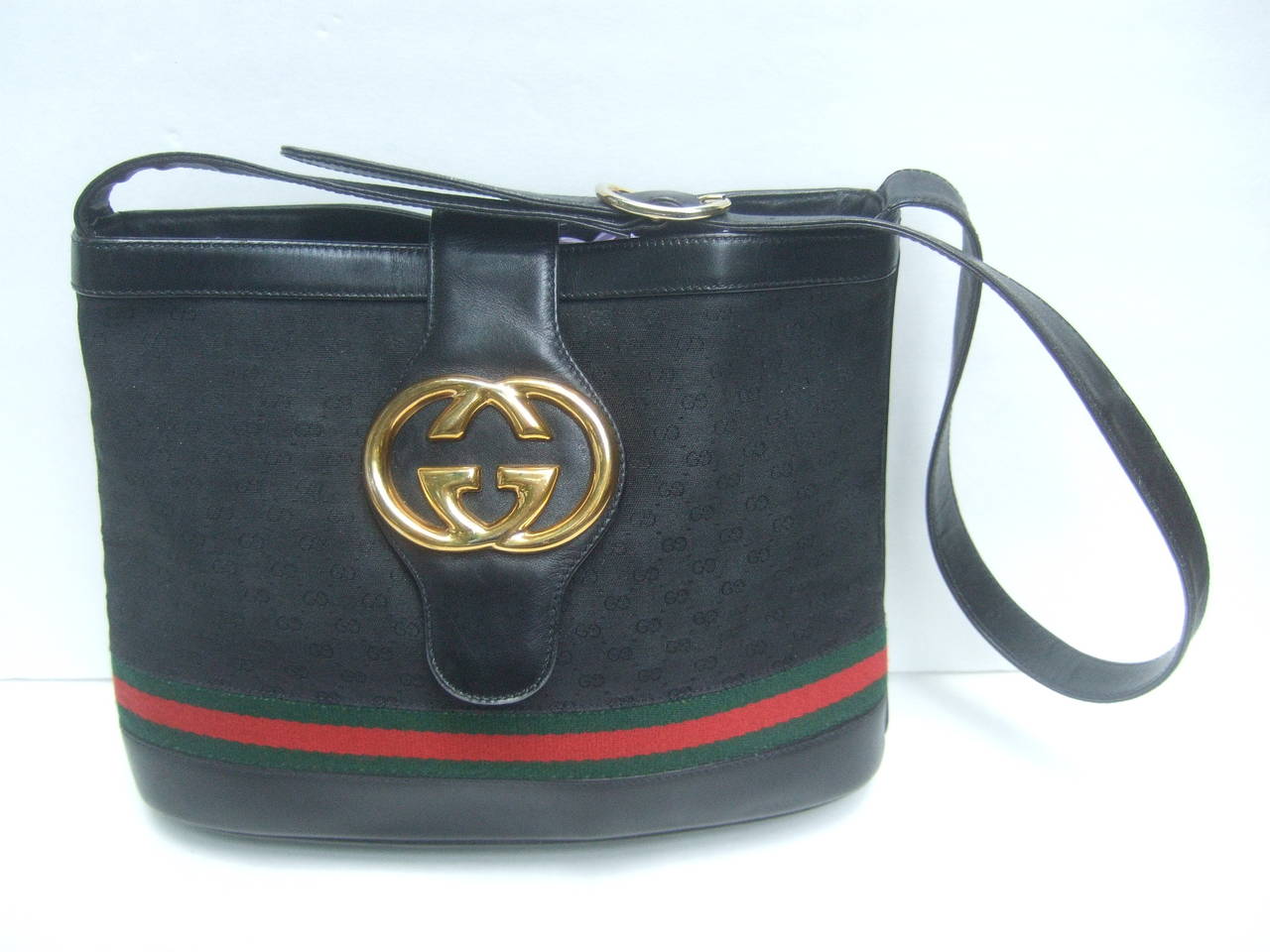 Gucci Black leather and canvas shoulder bag c 1980
The Italian handbag is adorned with Gucci's 
massive gilt metal interlocked initials 

The exterior covering is black canvas with 
Gucci's subtle initials accented with their
signature red and