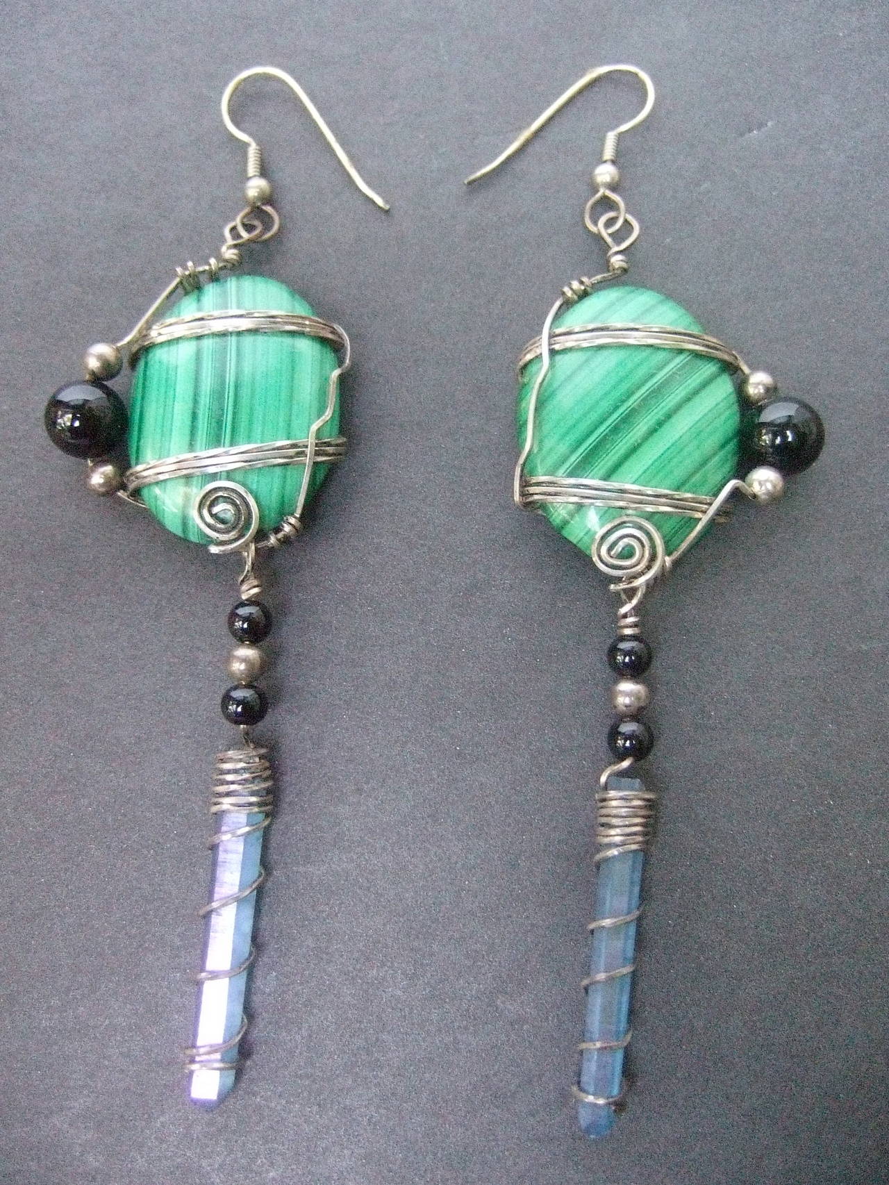 Sterling malachite crystal artisan dangle earrings
The unique handmade earrings are designed
with oval shaped malachite cabochons

The malachite cabochons are accented 
with sterling wire bands that wrap around
the stones

The malachite