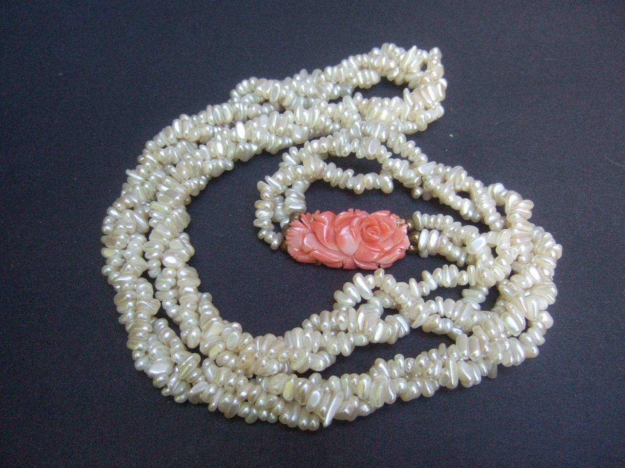 Opulent freshwater pearl carved coral braided necklace
The elegant necklace is designed with twisted strands
of oblong shaped freshwater pearls 

The necklace is embellished with a carved coral
medallion with floral designs. The carved coral