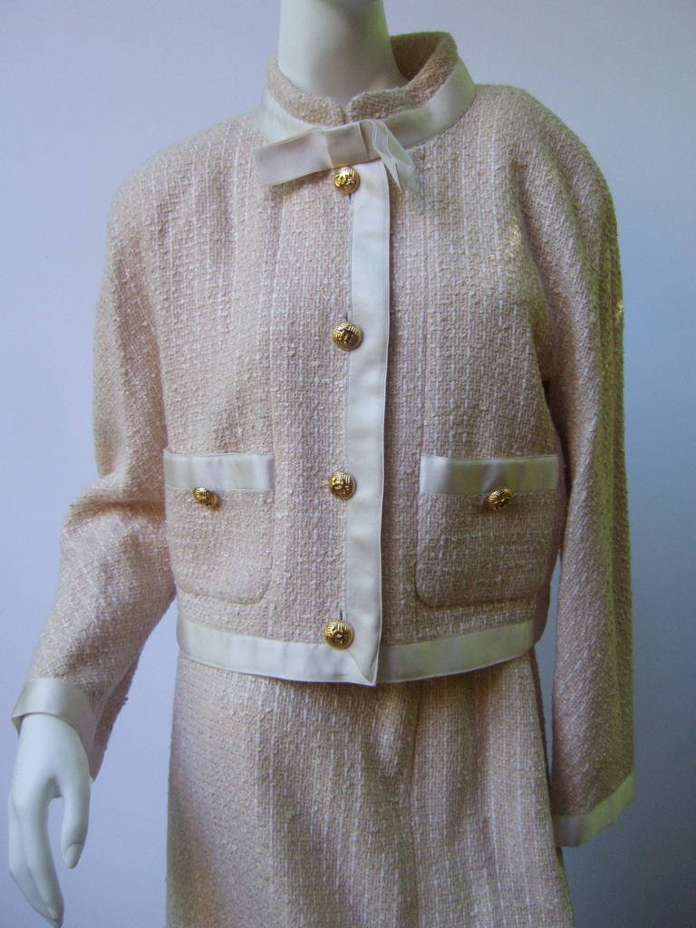 CHANEL Elegant ivory silk & wool skirt suit Size 44
The beautiful understated suit is designed with Chanel's  
signature accoutrements. Gilt metal C.C. initial buttons,
satin border trim & bow detail, gilt metal chain in the silk
lined