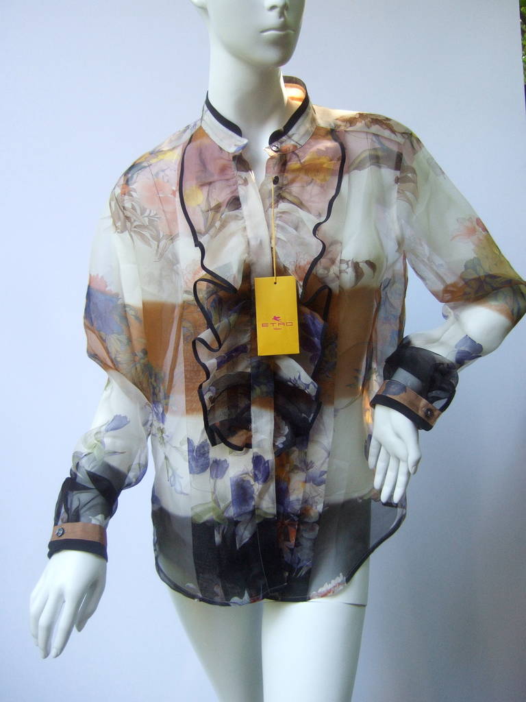 ETRO  Sheer silk floral blouse new with tags Size 44 
The chic blouse is designed with a mandarin style collar & a ruffled pleated panel running down the front. The small gray resin buttons are stamped:
ETRO

The sheer silk blouse is a field of