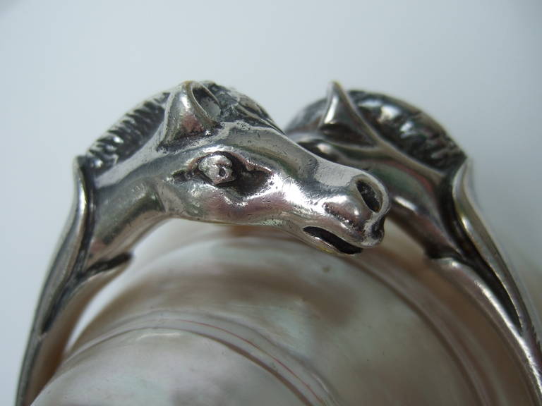 HERMES Paris Silver metal equestrian bracelet c 1950
The hand wrought bracelet is adorned with a pair
of horse heads. The equine are accented with etched
& impressed designs

The bracelet is stamped: HERMES Paris Made in France

The interior