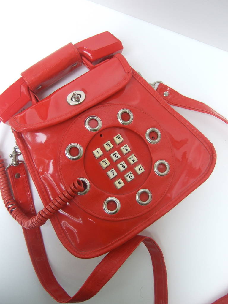 1970s Avant-garde mod red vinyl telephone handbag
The innovative handbag merges fashion & technology
The unique rare design is the predecessor of the cell
phone & the i-phones of today

The cord & telephone jack are concealed in the