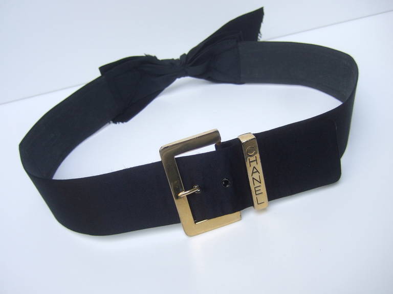 CHANEL Elegant black satin gilt buckle belt c 1990
The stylish belt is adorned with a sleek gilt
metal buckle stamped: CHANEL

The wide black satin belt has a bow embellishment
on the center back side. This unique detail allows
the belt to be