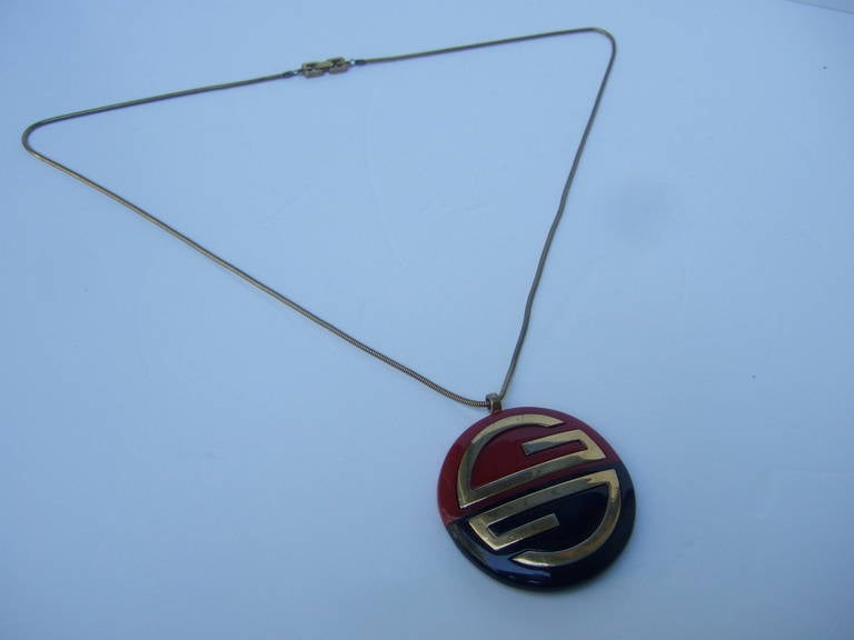 Givenchy sleek cinnabar & jet resin pendent necklace c 1977
The elegant necklace is designed with a circular resin
pendent with Givenchy's gilt metal interlocked initials

The large scale pendent hangs from a long sinuous gilt metal
snake