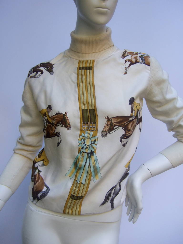 HERMES Paris equestrian silk & wool turtleneck sweater Size 42
The luxurious silk & wool sweater is illustrated with English 
style riders with jumping equine. The center silk panel is
designed with bridal buckles & a ribbon trophy

The