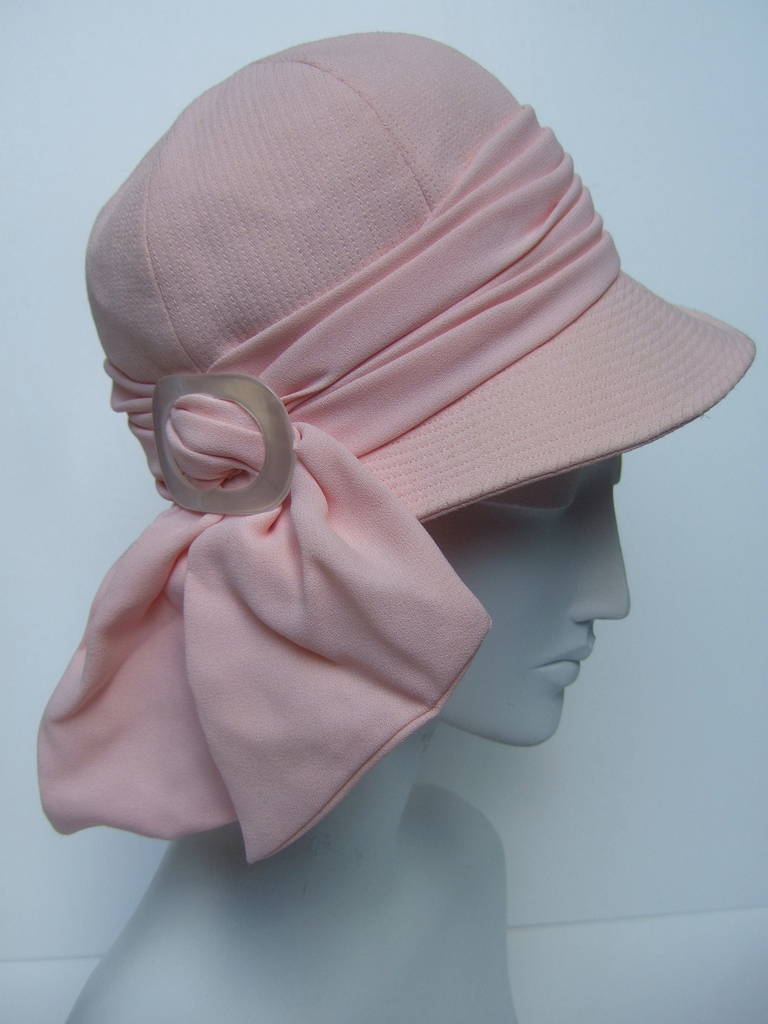 Yves Saint Laurent Pale pink bow trim hat c 1970
The stylish retro hat is designed with a billowy
bow with a pearly lucite buckle 

The interior is lined in aqua blue taffeta
Labeled: Yves Saint Laurent Paris
Paris New York

The interior