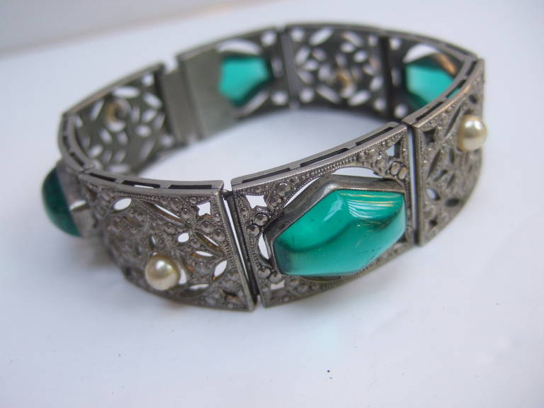 Art Deco 1930s Emerald glass cabochon maracasite bracelet
The opulent bracelet is embellished with four emerald color geometric glass 
cabochons. The filigree rectangular links are encrusted with steel cut maracasites 

Designed with four small