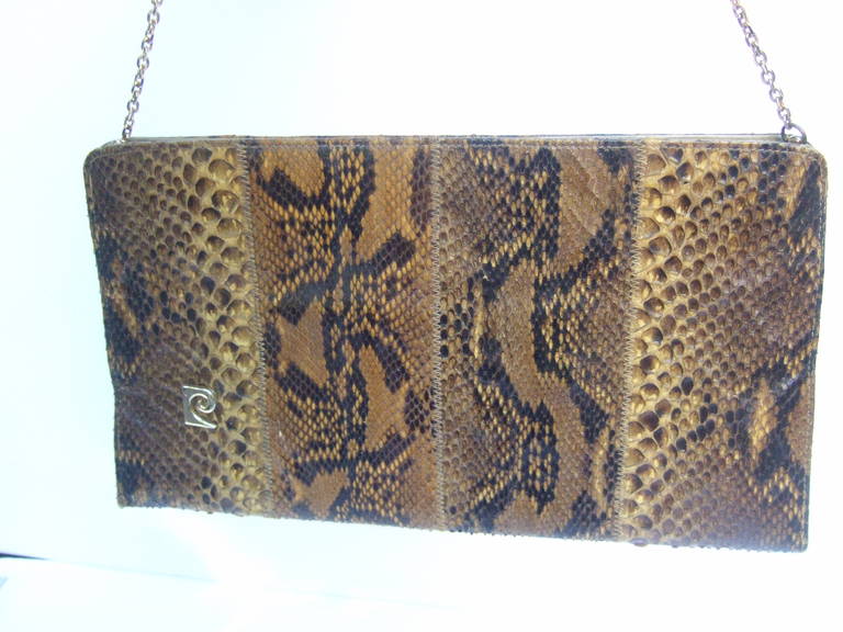 Pierre Cardin Sleek python versatile clutch bag c 1970
The chic handbag is covered with exotic python skin
The versatile designs converts from a mod clutch
Transitions to a stylish shoulder bag worn with the 
the gilt metal chain strap

The