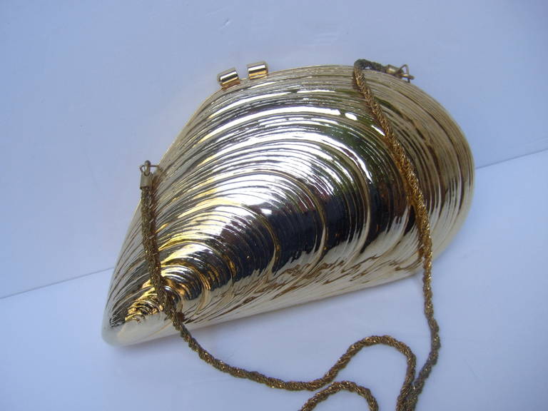 Opulent gilt metal clam shell evening bag Made in Italy c 1970
The exotic evening bag is designed in the shape of a clam shell
The versatile design transitions from a chic clutch by placing the
sinuous gilt chain strap in the interior

Converts