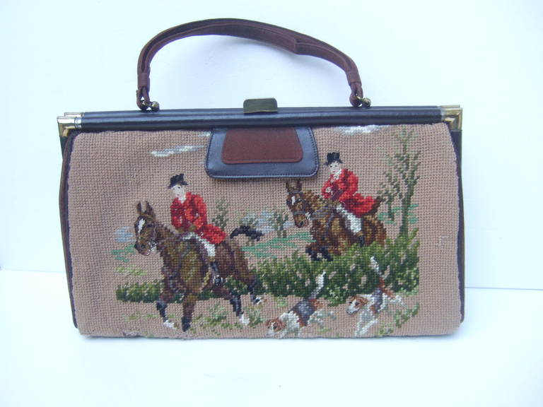 1950s Rare needlepoint fox hunt scene dual sided large handbag
The unique handbag is illustrated with fox hunt scenes on both sides
The scenes are different in design. Both sides have a pair of riders
astride their mounts followed by hounds in
