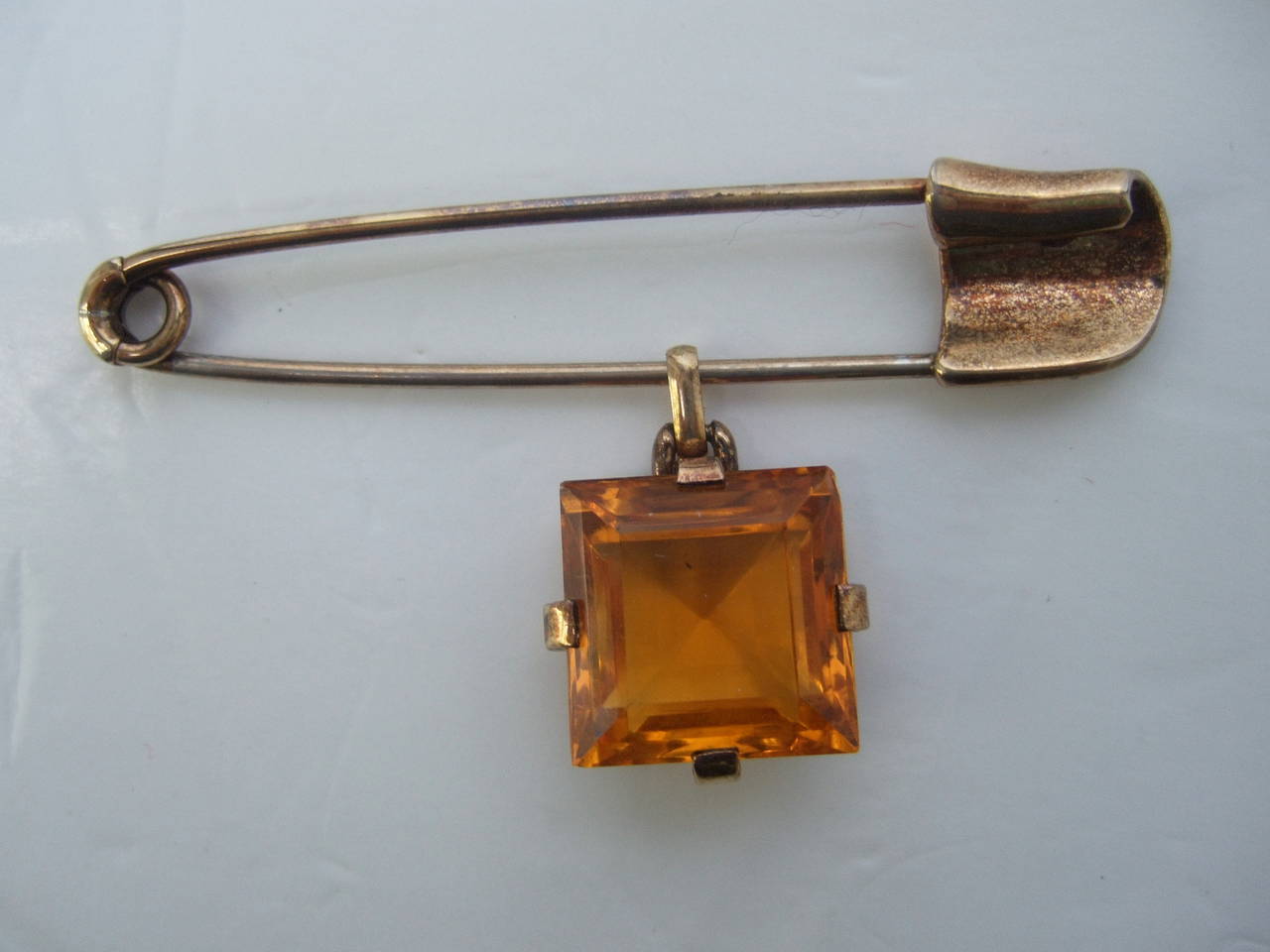 TRIFARI Art Deco unique safety pin brooch c 1950
The avant-garde brooch is designed with an citrine square cut dangling crystal
The large scale brooch is designed in the shape of a safety pin with gilt vermeil

Stamped: Trifari Pat Pend

The