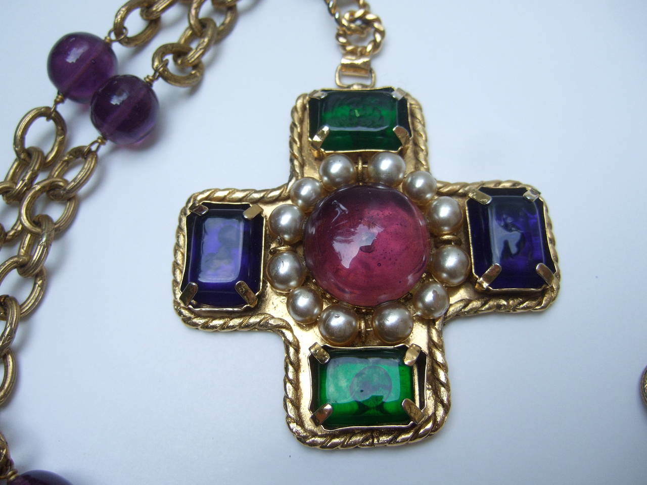 Chanel exquisite poured glass cross pendant necklace
The magnificent necklace is adorned with a jeweled cross pendant 
The cross is encrusted with a large center amethyst glass cabochon 
surrounded by a wreath of lustrous glass enamel