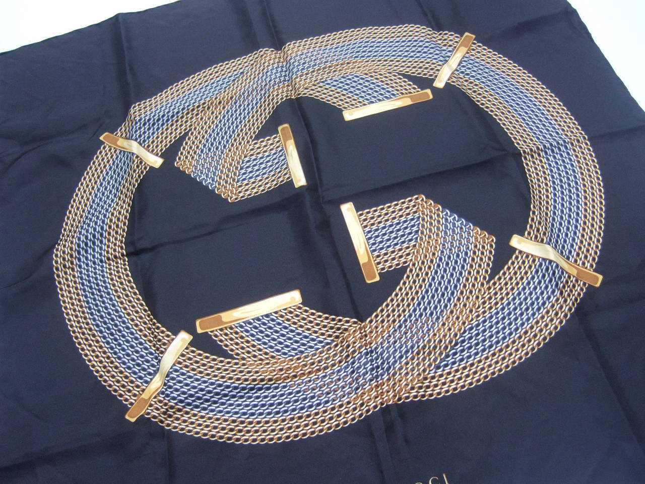 Gucci Italy Luxurious black silk logo scarf
The Italian hand rolled scarf is designed with Gucci's interlocked initials 
The G.G. initials are illustrated with rows of gold & silver chains

The stylish scarf makes a chic accessory

Designed by