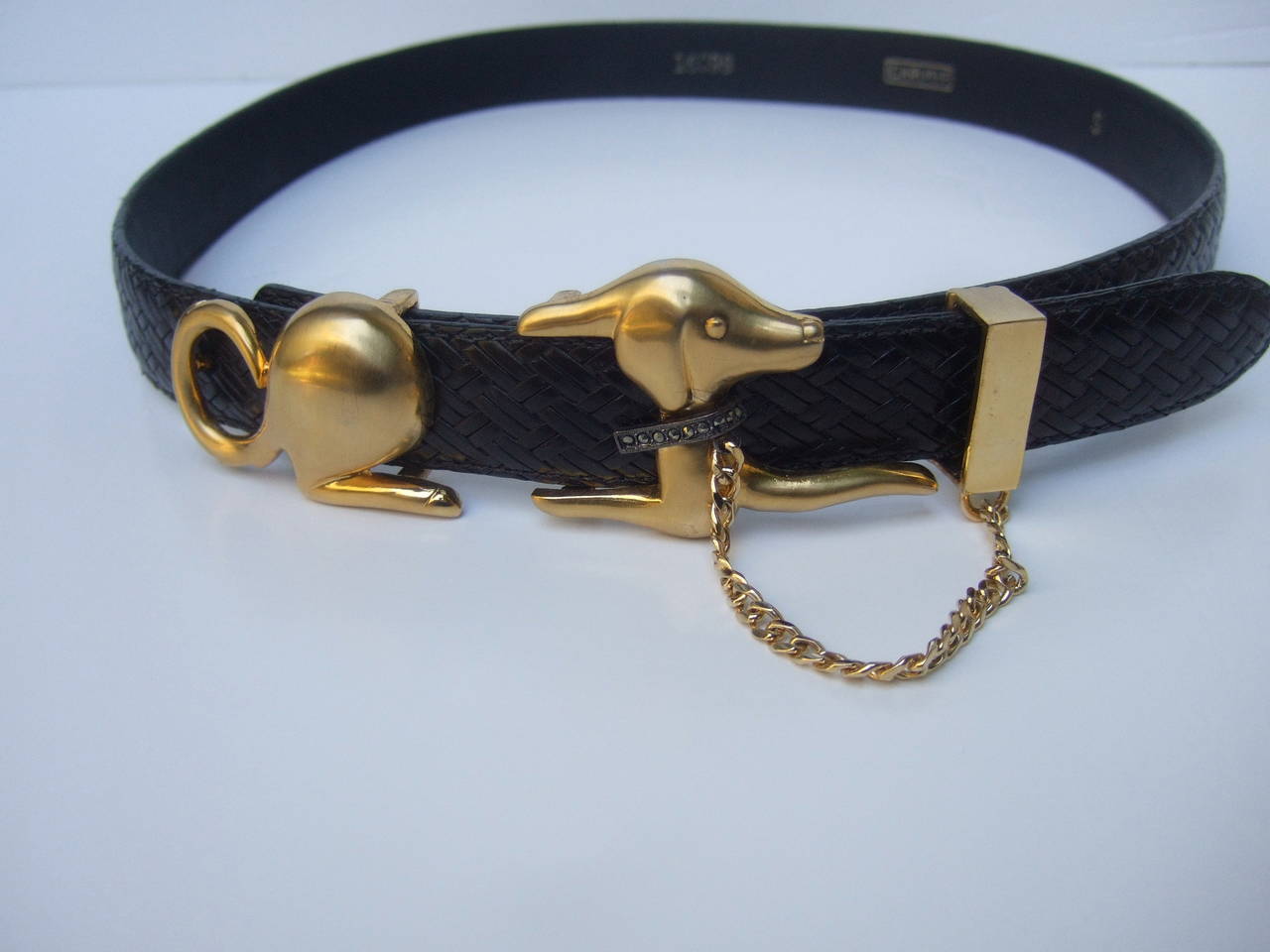 Stylish unique canine buckle black leather belt designed by Carlise 
The chic belt is designed with a matte gilt metal buckle with a dog
The dog has a subtle glittering marcasite collar & leash chain that hangs 
from the black leather belt

The