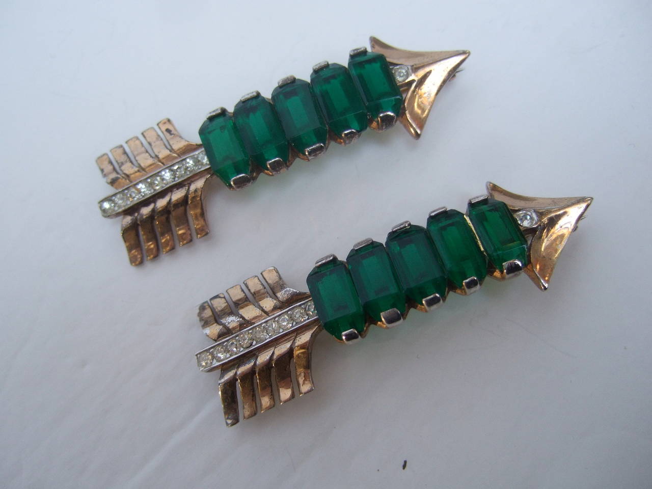 Art Deco Sterling arrow brooches c 1940s
The elegant pair of brooches are designed with a row of emerald green crystals

The brooches are sheathed in gilt vermeil accented with glittering diamante crystal settings

The severe design while