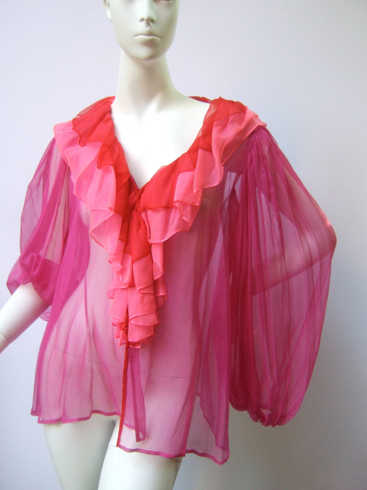 Yves Saint Laurent Rive Gauche Silk duster & blouse ensemble c 1970s
The stunning high fashion blouse & dramatic ruffled trim duster are designed with fuchsia, deep pink & crimson red sheer floaty silk that has an ethereal quality

The frothy