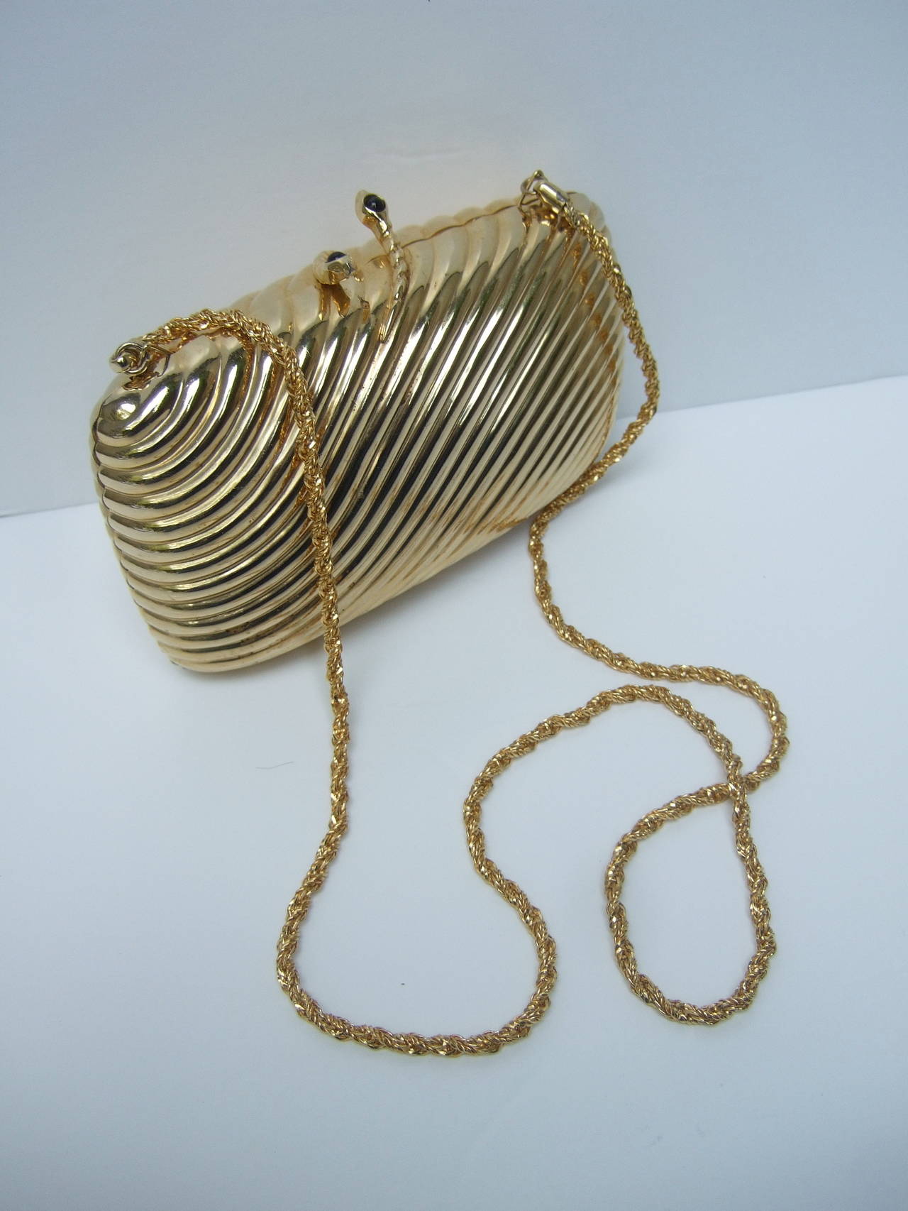 SAKS FIFTH AVENUE Opulent Gilt metal serpent evening bag Made in Italy  
The elegant clutch style evening bag is adorned with a pair jeweled serpents that serve as the clasp. Both serpent's are embellished with a small jet glass cabochons. The