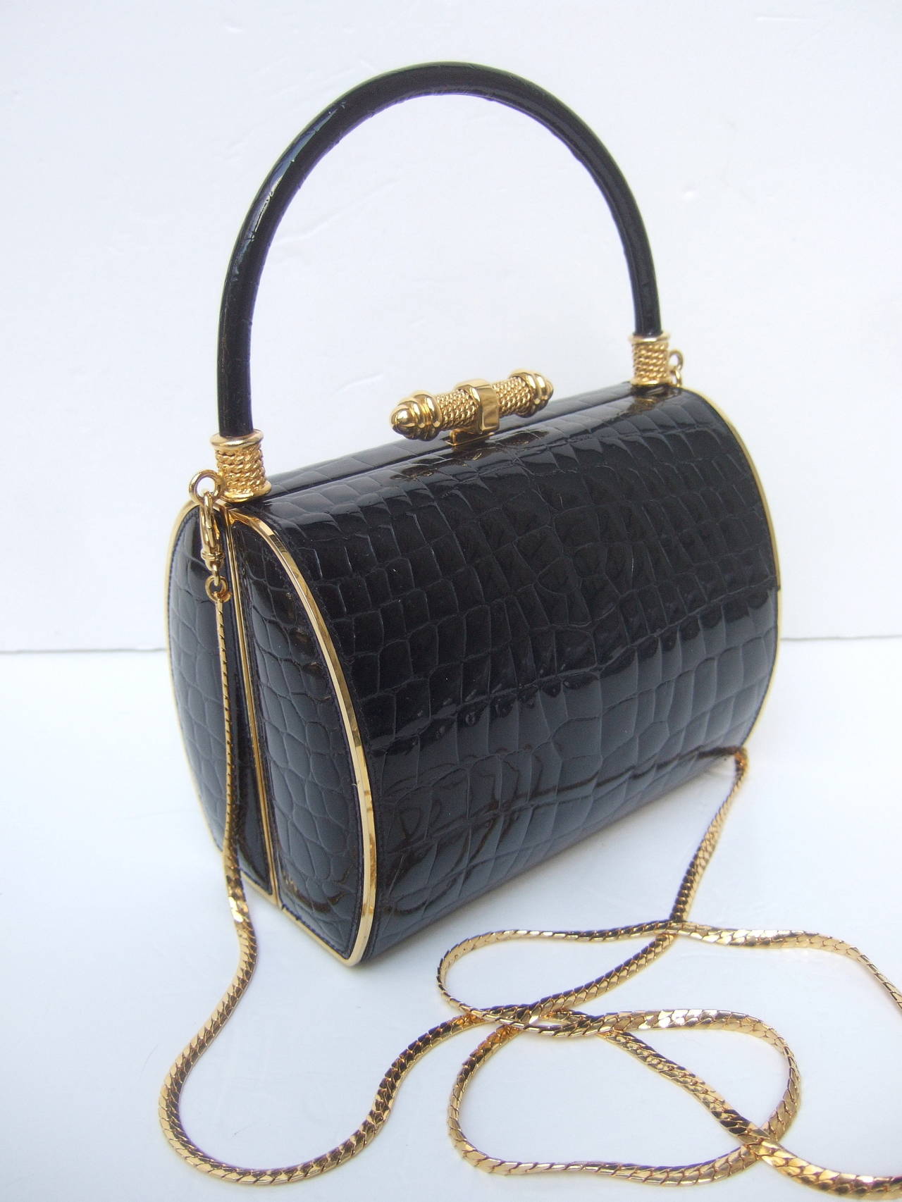Elegant black embossed patent leather handbag designed by Finesse La Model 

The chic desiger handbag is covered with sleek black embossed leather that emulates reptile skin. The ornate clasp & hardware are shiny gilt metal accented with