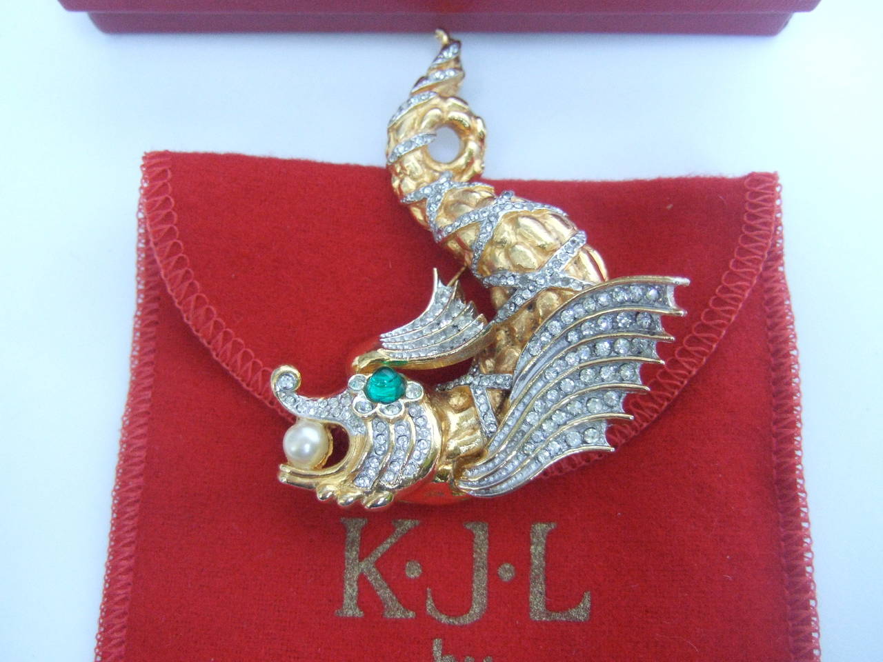 Ken Lane Jeweled crystal fish brooch 
The ornate figural brooch is encrusted with glittering pave crystals
The fish's eye is embellished with an emerald green glass cabochon
The fish is designed with a lustrous faux enamel pearl embedded 
in its