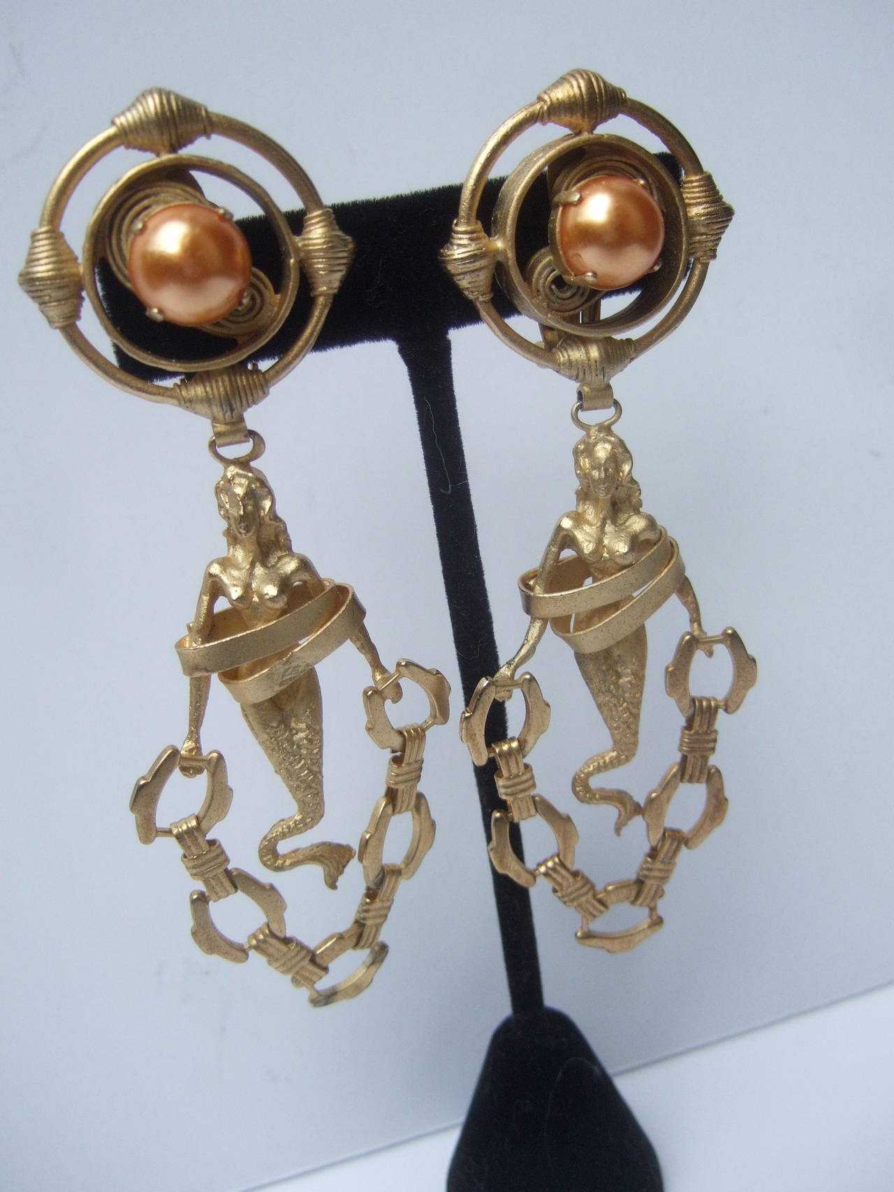 Italian artisan handmade gilt metal mermaid statement earrings designed by Particolari. The chic designer earrings are constructed with matte gilt metal
The huge runway style earrings are designed with figural mermaids with bands of gilt metal