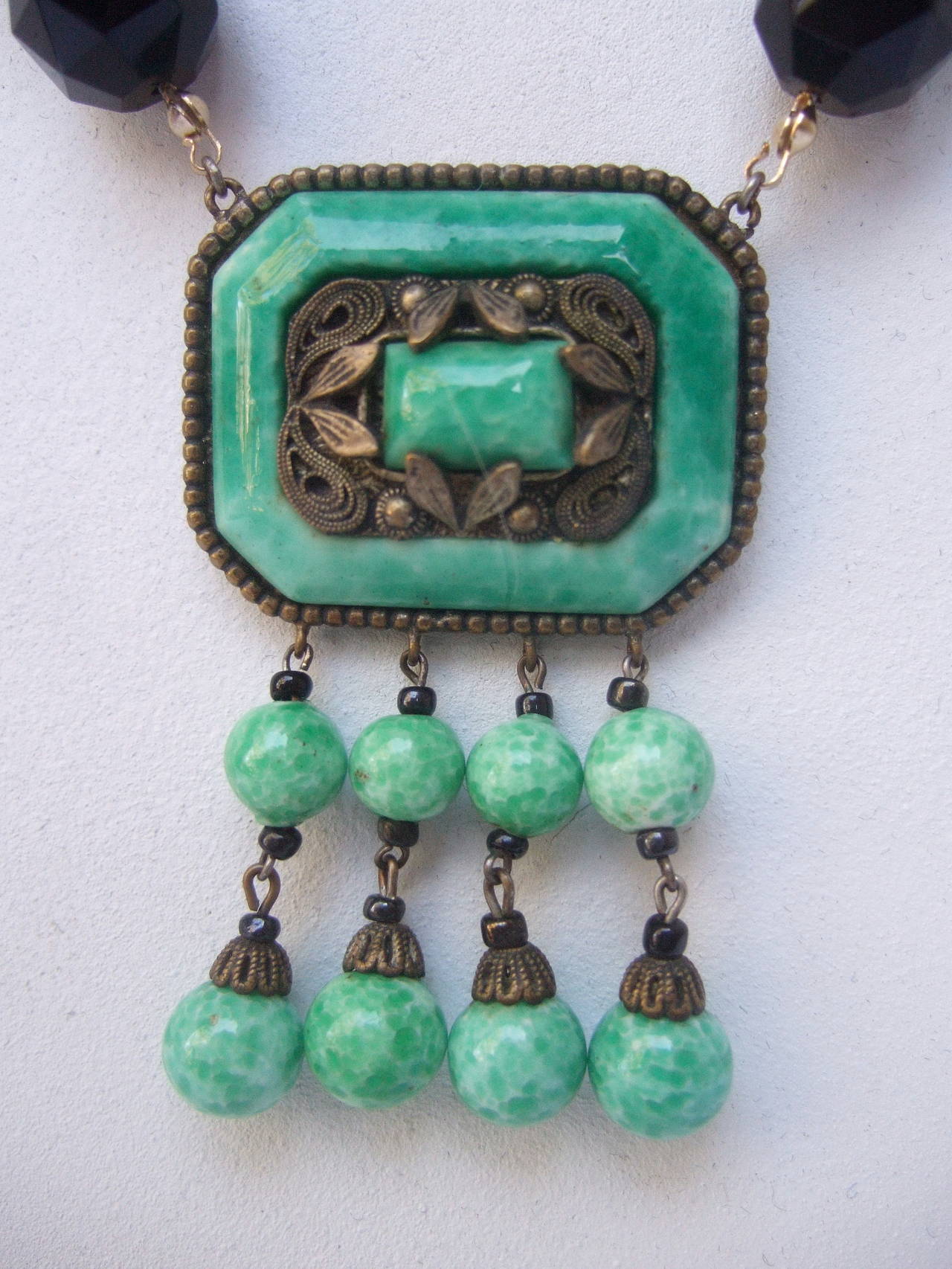 Art Deco Egyptian revival glass beaded necklace c 1930
The opulent necklace is designed with jade color opaque round glass beads interspersed with faceted black jet glass beads

The two graduated rows of glass beads transition into a rectangular