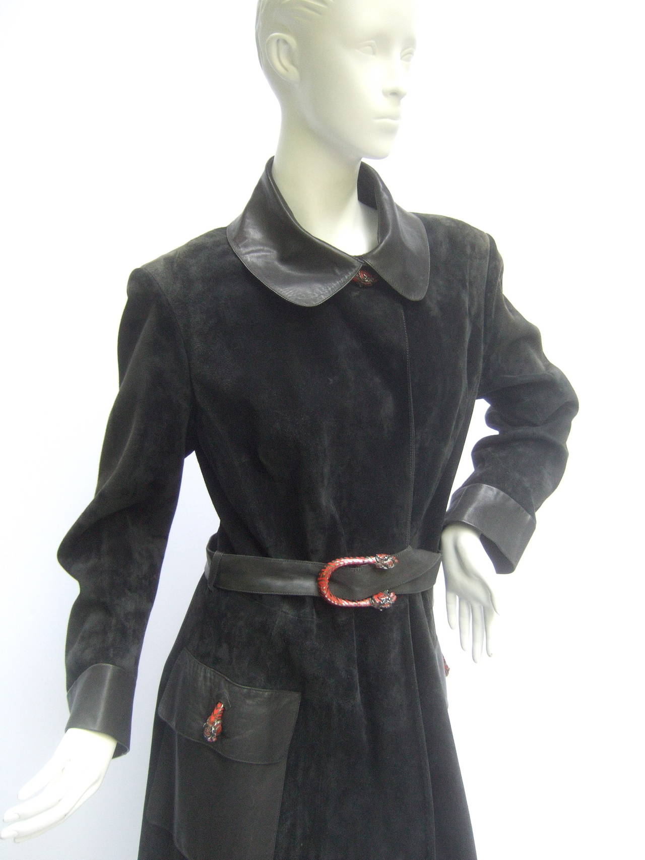 Gucci Sleek black doeskin suede trench coat with sterling silver tiger buckle & buttons. The stunning coat is plush doeskin suede contrasted with buttery soft black leather cuffs, belt, collar, & deep patch pockets
  
The rare Gucci coat is