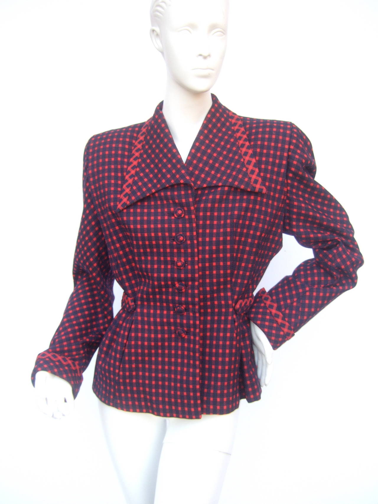 1940 Favolosa giacca a quadri in lana rossa e blu. La giacca in stile art déco è progettata con un ampio e drammatico colletto a punta. La giacca retrò chic si chiude con sei bottoni coperti in tinta. La giacca è disegnata con una cintura di