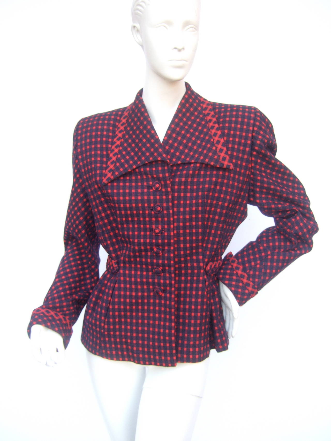 1940s Fabulous red & blue wool checked jacket. The art deco style jacket is designed with a wide dramatic pointed collar. The chic retro jacket closes with six matching covered buttons. The jacket is designed with a cinched  stationary belt on the