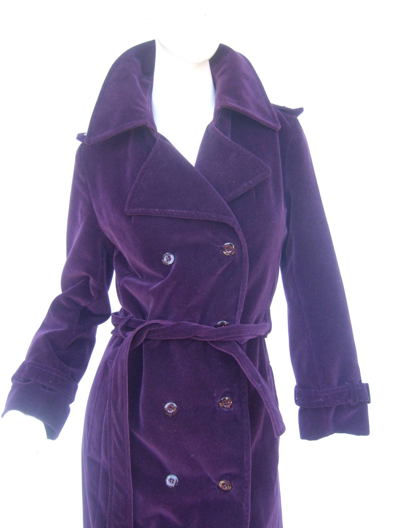 Saks Fifth Avenue Amethyst velvet belted trench coat c 1980  US Size 6
The stylish coat is designed with plush dark egg plant color purple velvet with eight resin buttons. The high fashion coat is designed with epaulet detail on the shoulders &