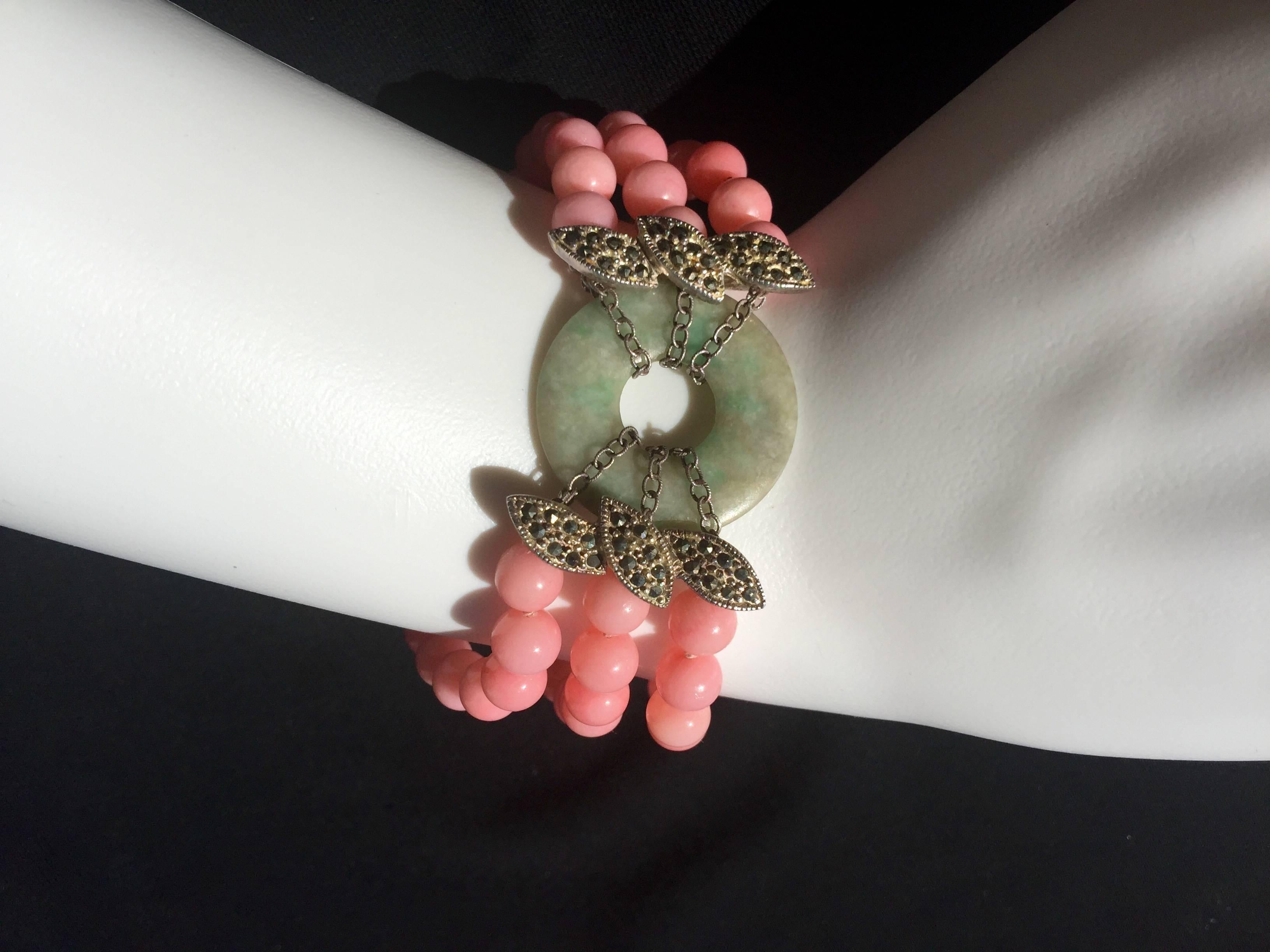 
This is just so pretty!  

Three rows of soft pink enhanced coral beads are all hand knotted.

The bracelet has a lovely piece of jade at it's center; displayed on sterling
silver chains.

The jade is a subtle, mottled spring green