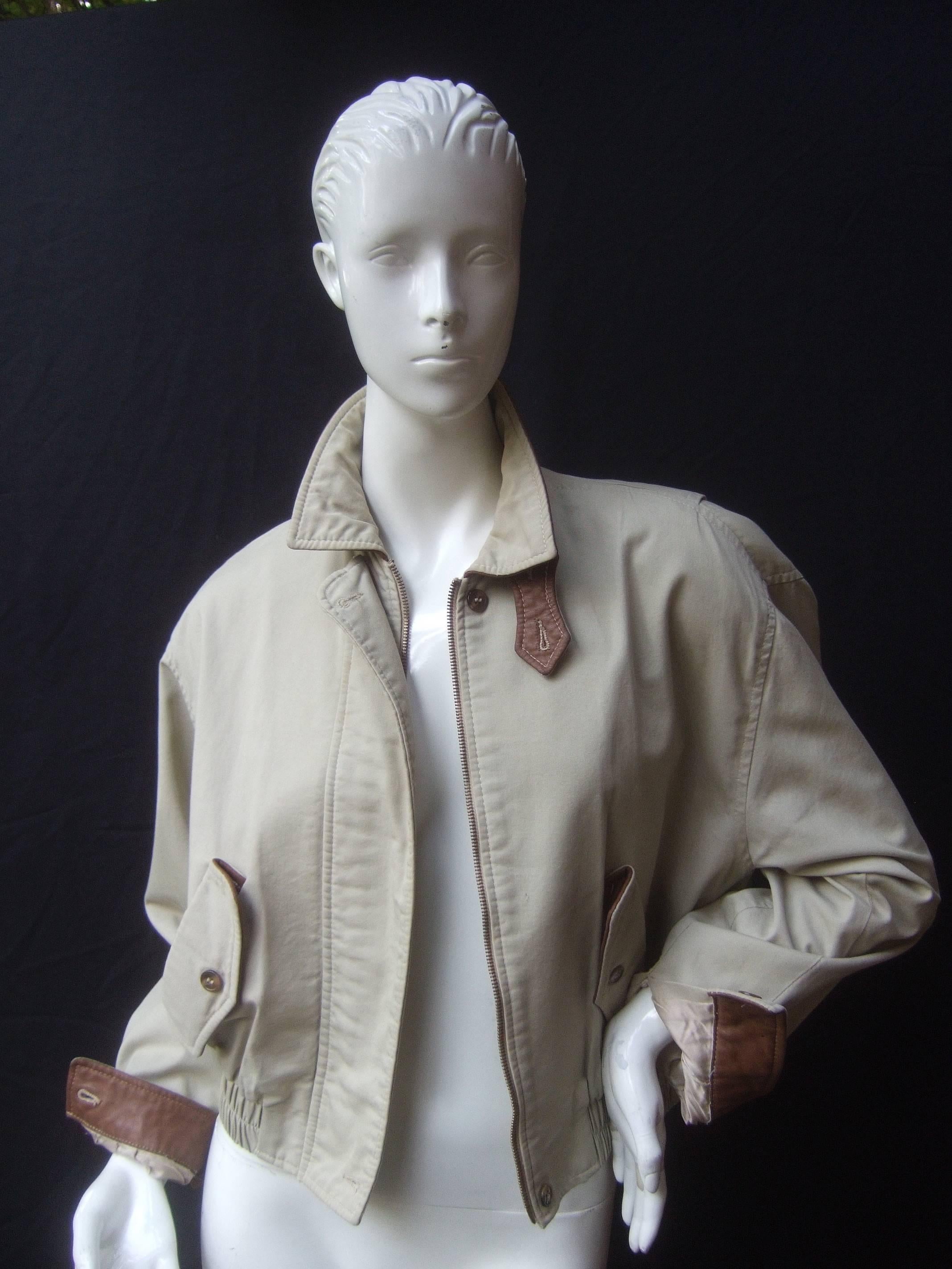 Burberry's London women's Eisenhower style jacket c 1980s
The classic tan cotton jacket is accented with a brown
leather lined collar. The sleeve cuffs are also lined with
brown leather. The collar and cuffs can be folded to 
revel the brown