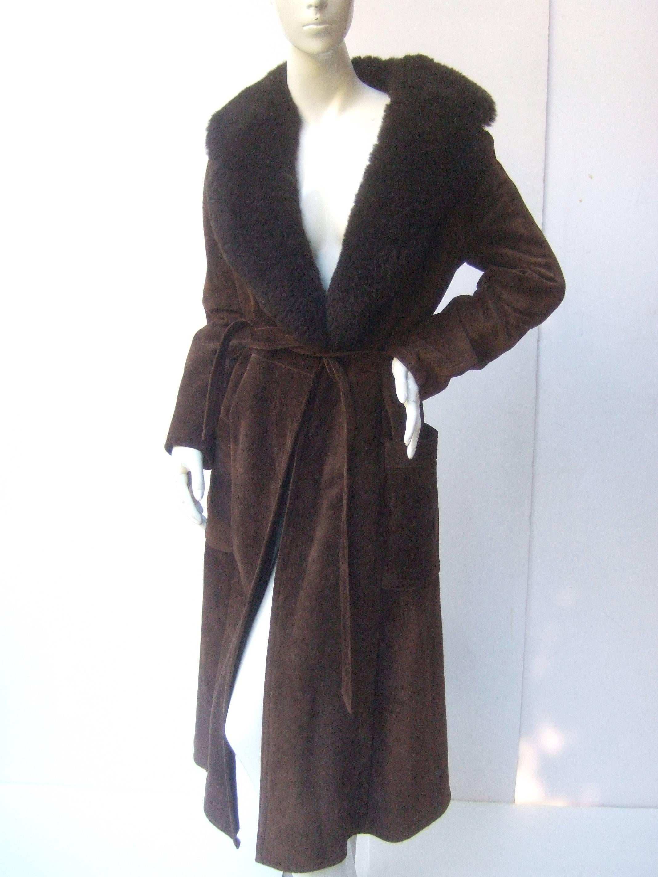 Saks Fifth Avenue Brown suede belted coat c 1970s
The vintage brown suede coat is designed with 
a wide lamb fur collar

The belted suede coat has two deep pockets
on both sides of the front. The inside is lined
in plush brown faux fur

The