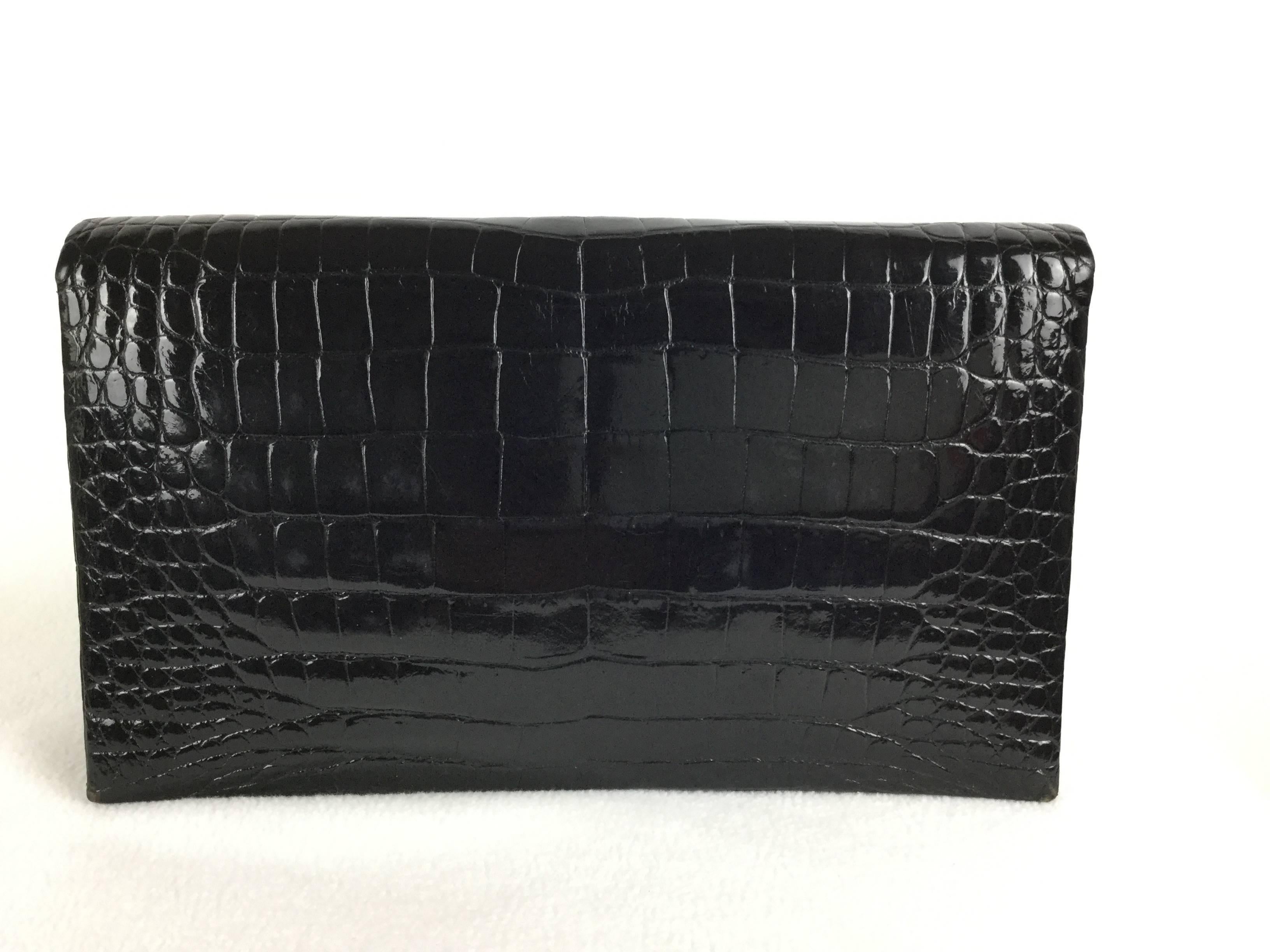

What an amazing Deco Revival, early 1970's, convertible clutch/shoulder bag in sleek black crocodile with enamel trim and a subtle but colorful floral focus enlivened by marcasites.

The Deco-Style enamel clasp is just gorgeous against the
