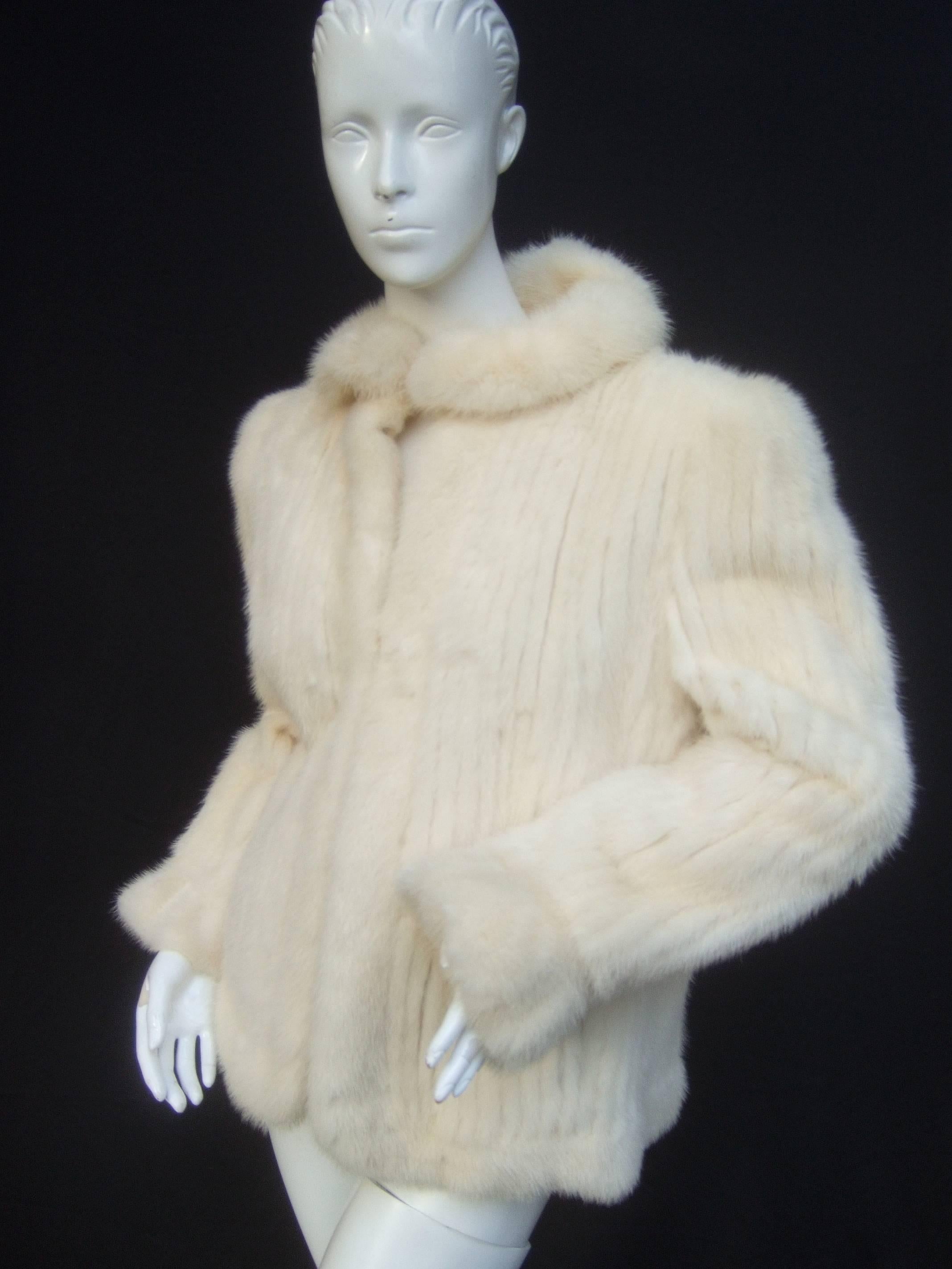 Luxurious ribbed pearl mink fur jacket c 1980s
The elegant vintage fur jacket is designed 
with plush mink fur throughout

The collar, center opening, hemline and 
cuffs are framed with mink fur bands 
The front, backside and sleeves