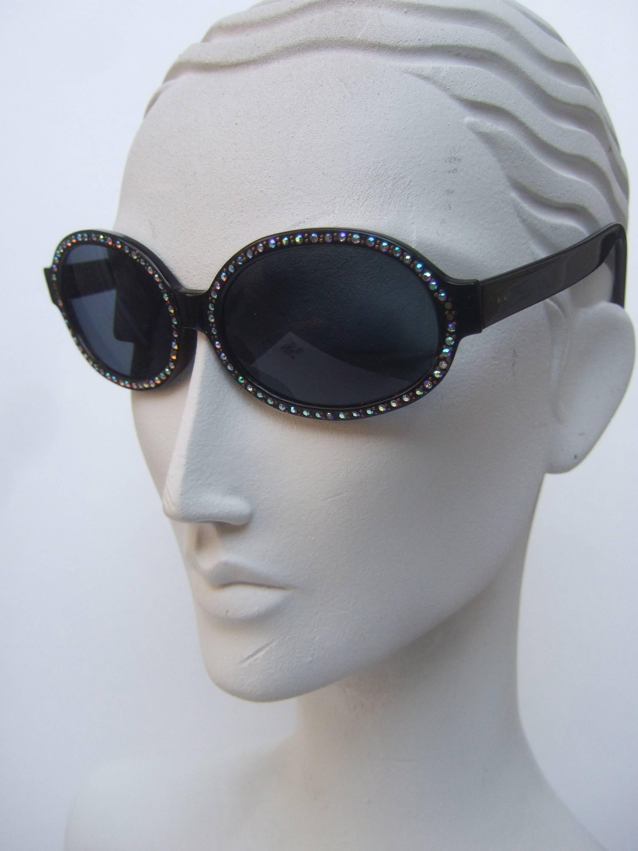 Chic black luicte crystal trim tinted sunglasses Made in France
The stylish eyeglasses are embellished with 
glittering auroraborealis crystals that circle 
the oval glass tinted lenses

The tinted glass lenses are gray in color 
The handmade