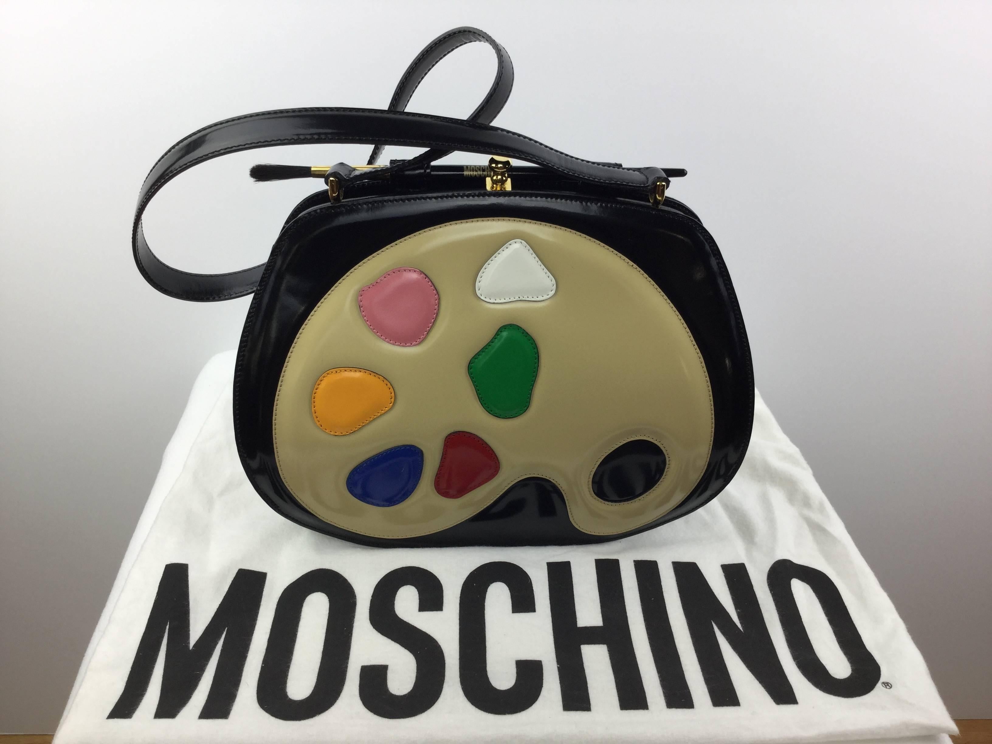 
Fabulous Moschino bag made in Italy by Redwall. 

Super rare!  Iconic.

Designed as an artists palette complete with a real paintbrush
adorning the top.

Made of shiny patent leather.

Interior lined with jacquard fabric with one zipper
