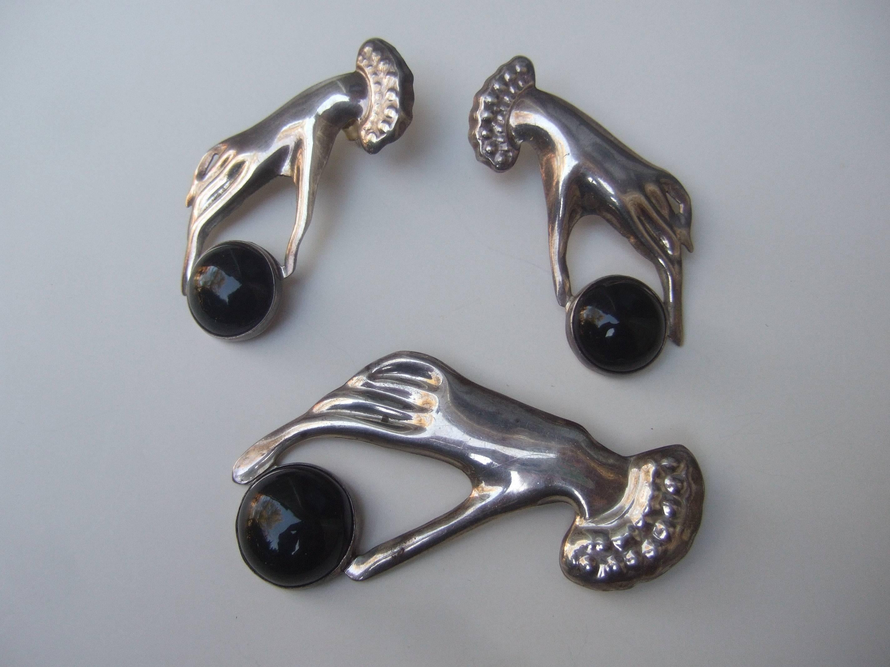 Mexican sterling figural hand brooch & earring set 
The unique large scale brooch & matching 
pierced earrings are adorned with a large
black glass cabochon 

The stylized artisan brooch & earring set
makes a very dramatic accessory 

The