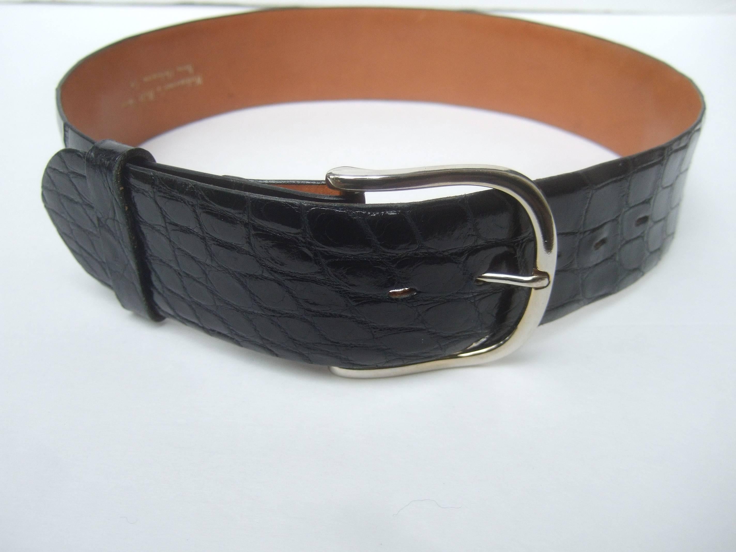 Exotic ebony genuine alligator women's belt ca. 1980s
The sleek wide black reptile leather belt is 
adorned with a large chrome metal buckle

The classic high fashion reptile skin belt makes
a very chic accessory

Stamped Genuine Alligator