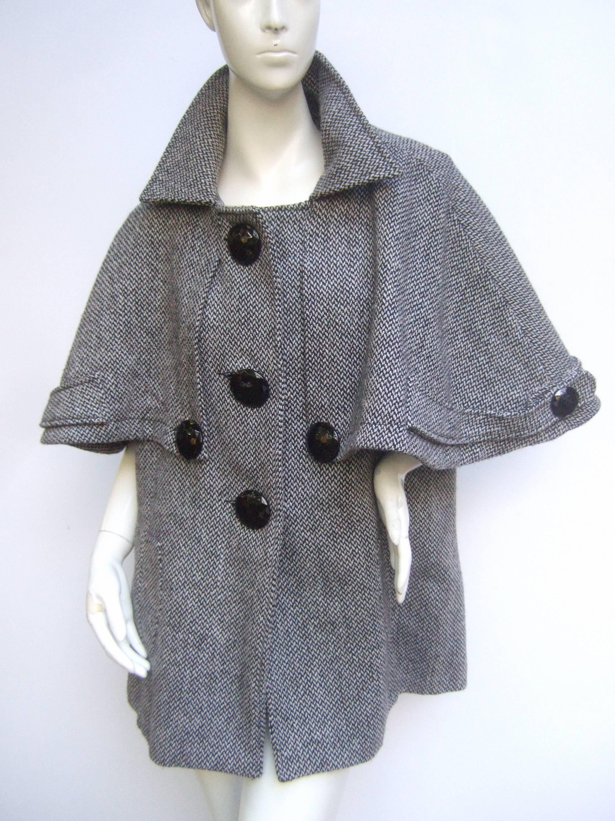 Stylish unique capelet herringbone wool blend 3/4 coat
The high fashion short length coat /cape is designed
with wide flared cape style shoulders

The capelet style coat is adorned with large
circular black faceted buttons. The salt and
pepper
