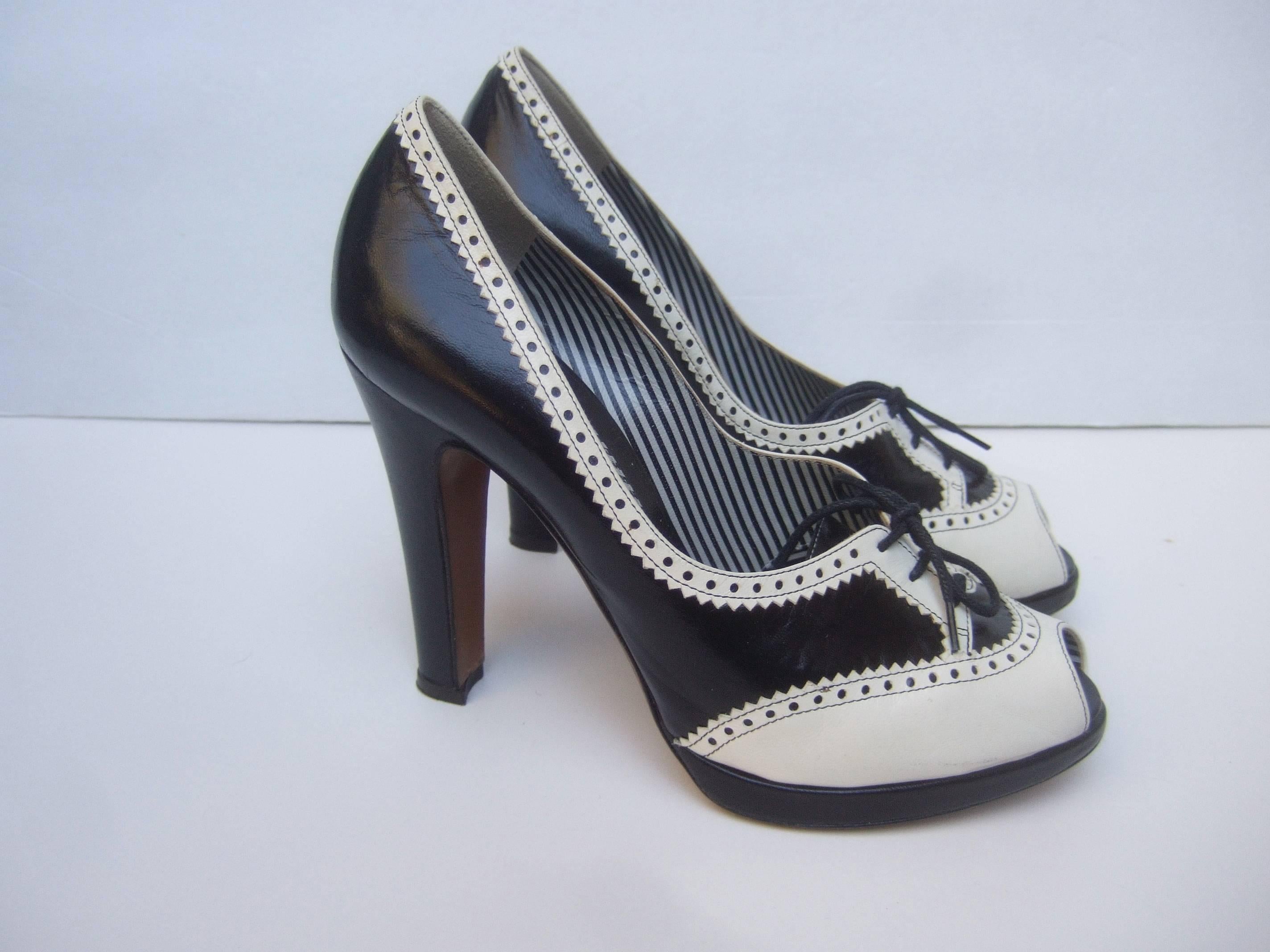 Moschino Italy Black & white leather peep toe pumps Size 39.5
The stylish high fashion shoes are designed with contrasting
leather with perforated trim

The peep toe design is accented with lace up ties
The sides and back of the Italian pumps