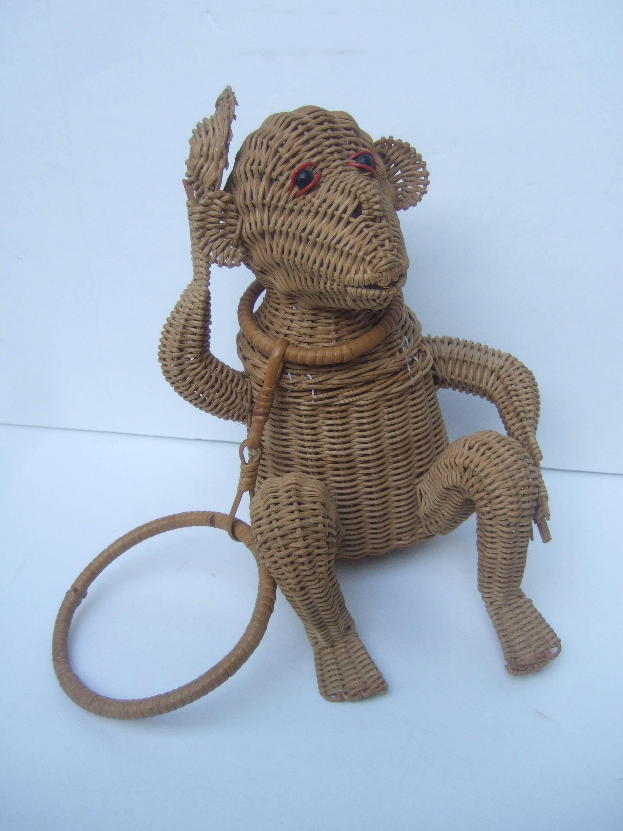 Whimsical wicker monkey novelty handbag ca. 1960
The unique artisan handbag captures a charming
monkey with black beaded eyes tipping his hat

The charming wicker monkey handbag is carried
with a circular wicker handle. The back side of
the