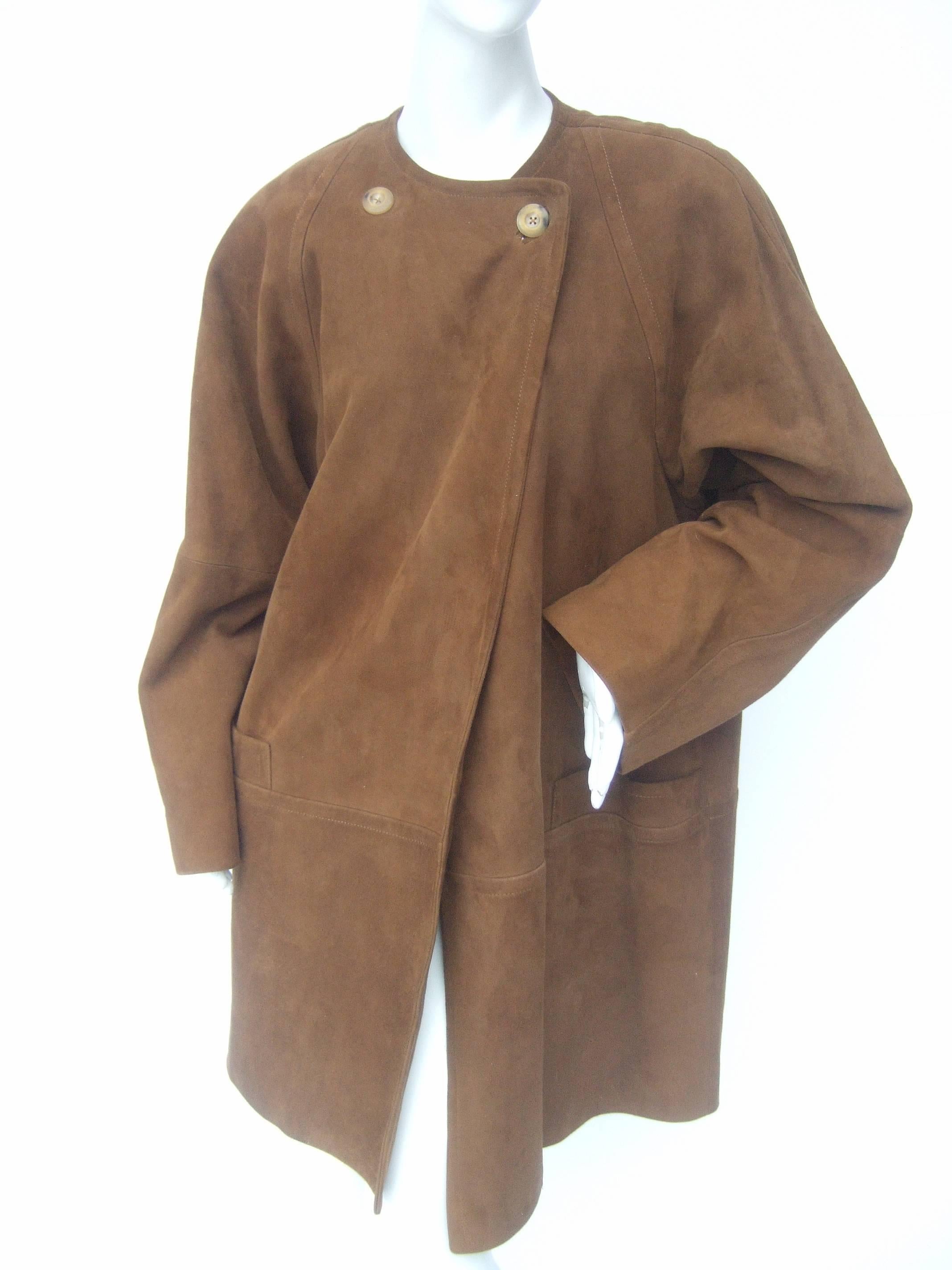 Jaeger Stylish brown doeskin suede duster coat
The classic light weight coat is designed with 
plush suede. The neckline has a pair of lucite
horn style buttons that exclusively secure
the coat. The lower front section remains
loose and does