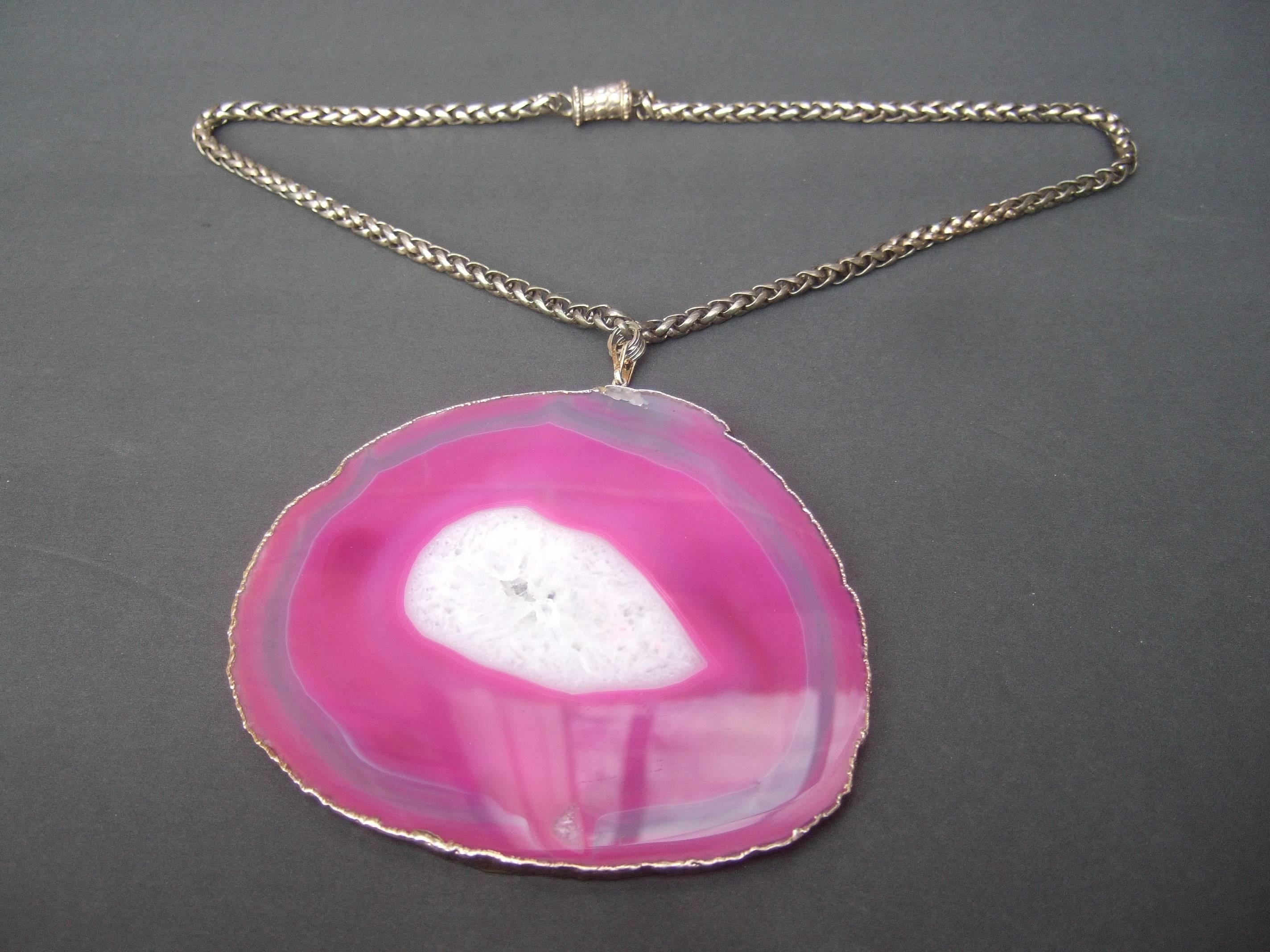 Massive fuchsia sliced agate pendant necklace
The avant-garde artisan necklace is adorned
with a huge sliced agate tile encased is a 
hammered metal bezel that frames the organic 
contours 

The large sliced agate is suspended from a
