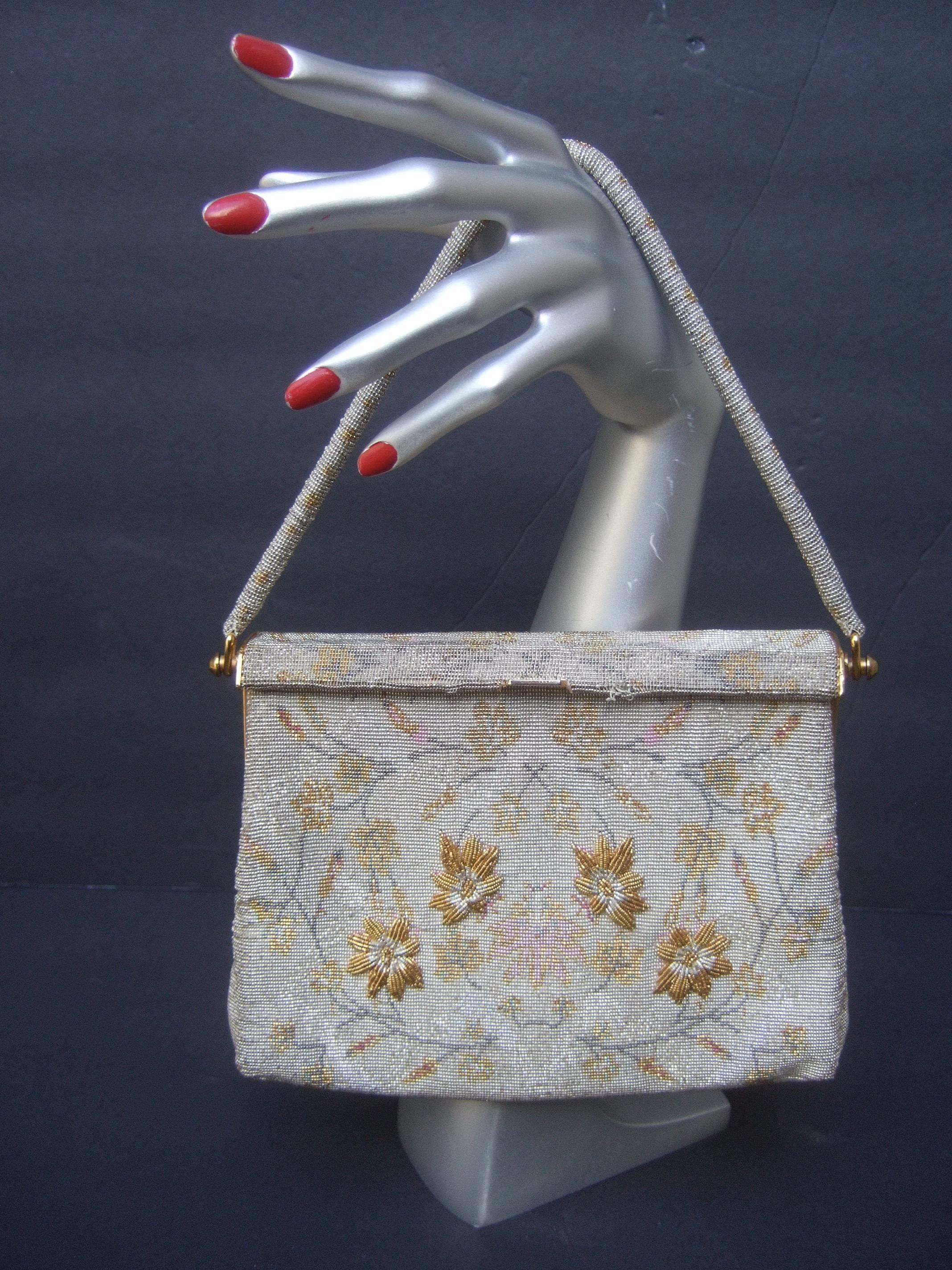 Exquisite glass beaded floral evening bag ca 1960
The elegant purse is embellished with intricate 
tiny glass micro beads. Illuminated with gold
metallic flowers set against a silver glass beaded
background 

The front exterior is designed with four