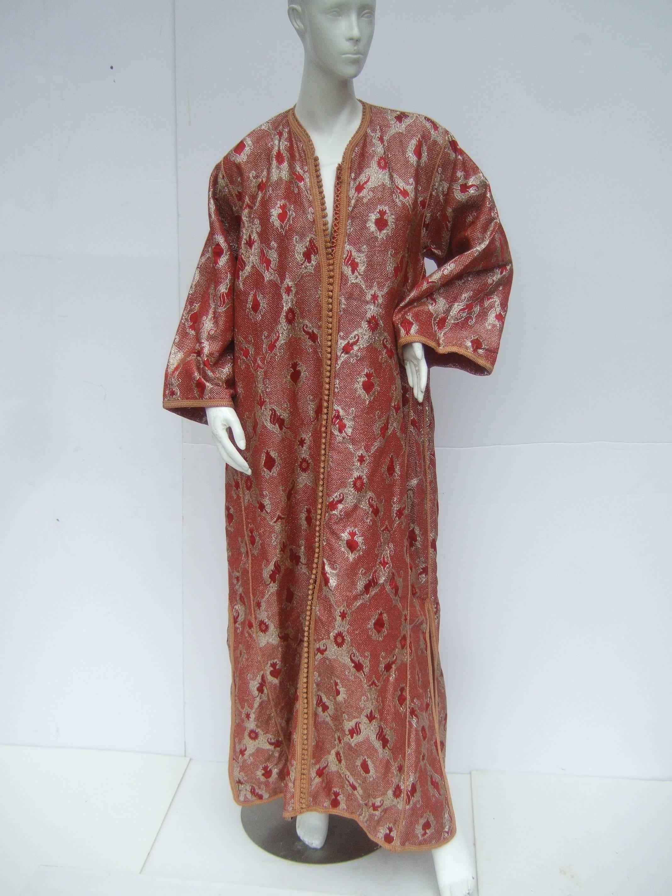 Exotic metallic brocade caftan gown c 1970s
The luxurious caftan is designed with 
brilliant gold metallic combined with 
deep red accent colors 

The front of the elegant caftan gown 
is embellished with a vast row of crochet 
knit buttons