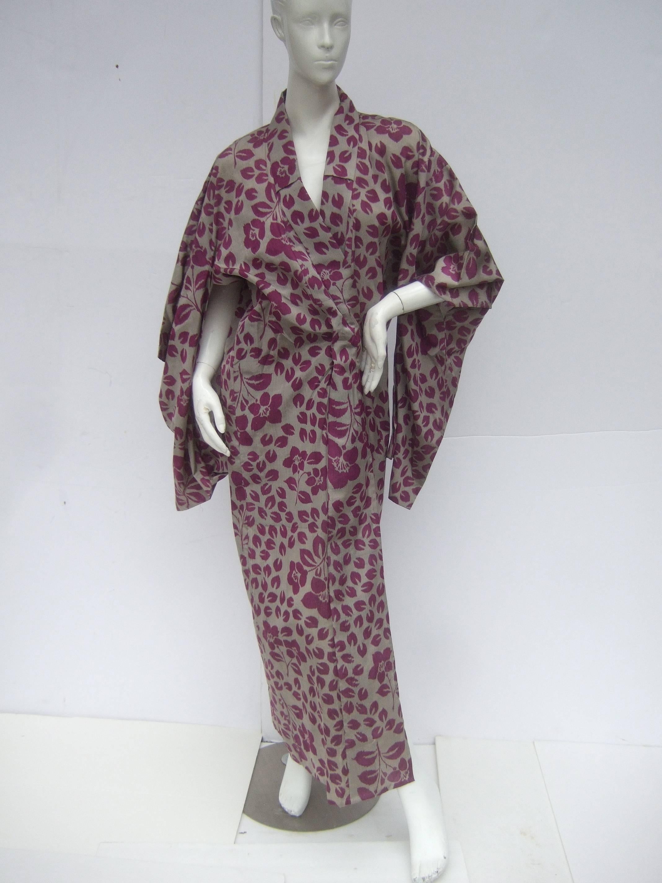 Japanese style flower print kimono robe c 1970s
The exotic kimono is designed with a series
of purple flower blooms and fallen flower
pedals scattered throughout the print

Designed with traditional long exaggerated
sleeves. The sheer light