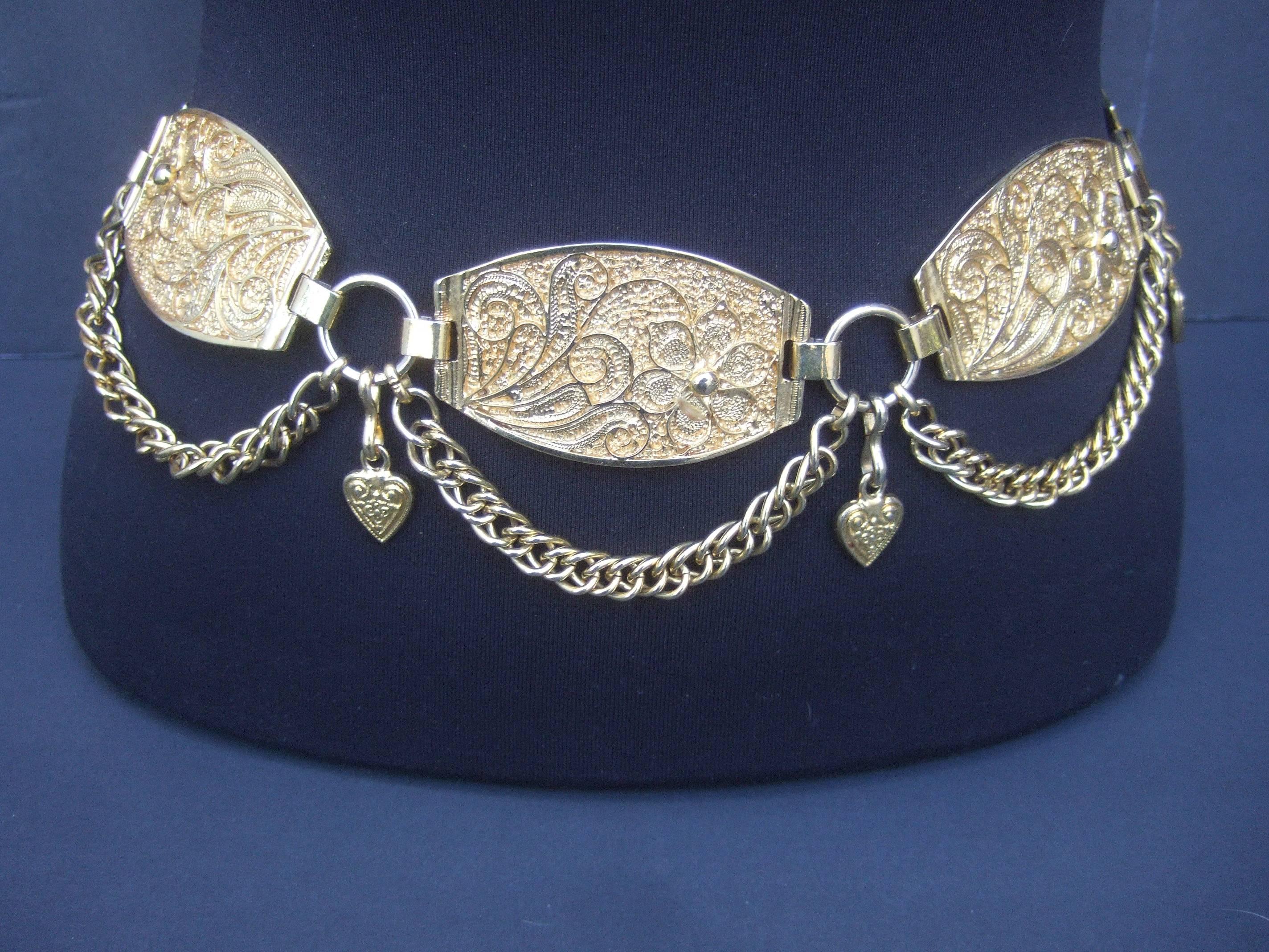 Neiman Marcus Italian gilt metal medallion belt
The unique belt is designed with heavy gilt metal
links with intricate scrolled flowers  

Suspended from each medallion are chunky 
gold metal chains with dangling heart charms

The ornate gold