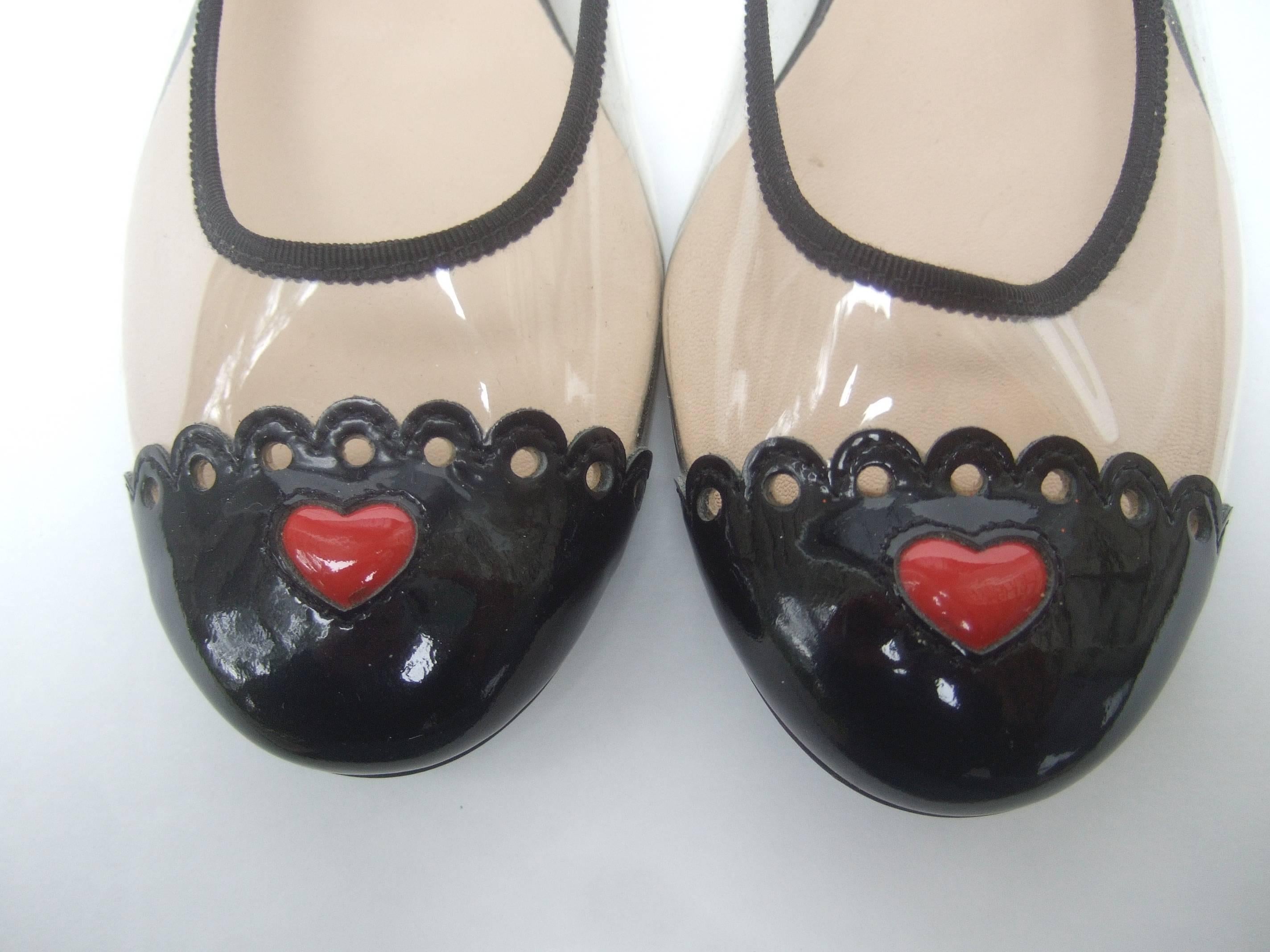 Moschino Cap toe ballet style flats in box Size 38
The stylish designer flats have red patent hearts
symbols on the toes

The sides are designed with clear vinyl with
black patent leather trim. The top edges are
framed with black ribbon trim